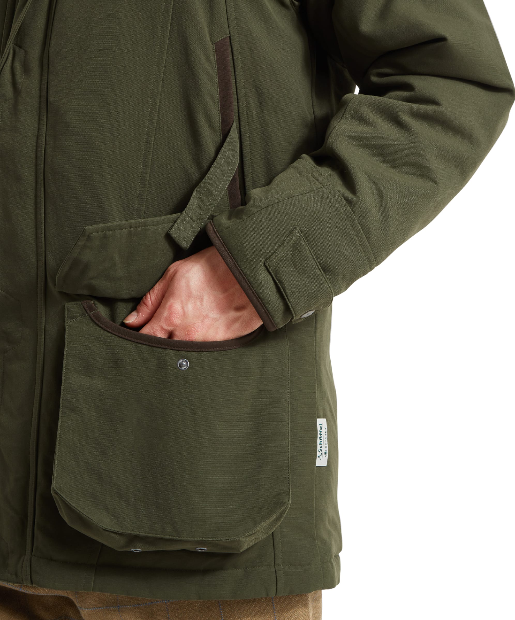 A man demonstrating the handwarmer pockets of the Schöffel Ptarmigan Classic Coat for Men in Green, with one hand in the pocket, emphasizing practicality and comfort.