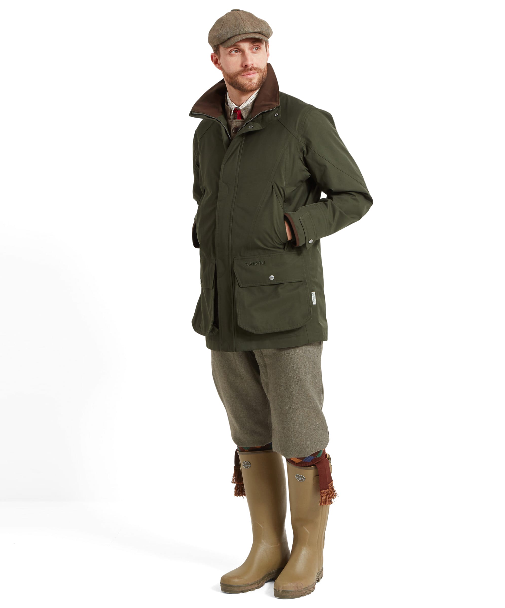 Full-body view of a man dressed in the Schöffel Ptarmigan Extreme II for Men in Green, paired with khaki trousers and wellington boots