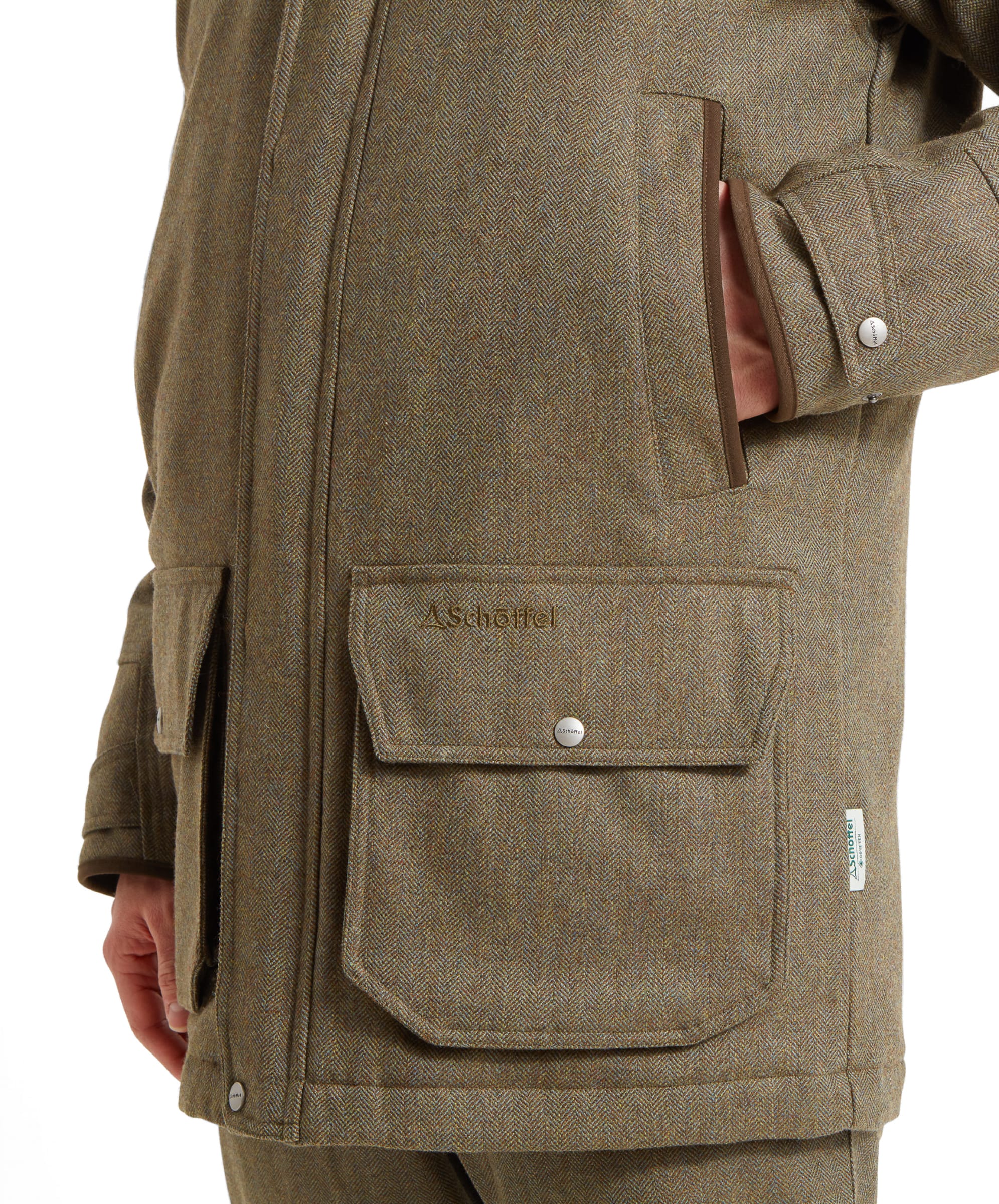 Close-up of the front pocket on the Schöffel Ptarmigan Tweed Classic Coat for Men in Green, showing the Schöffel logo.