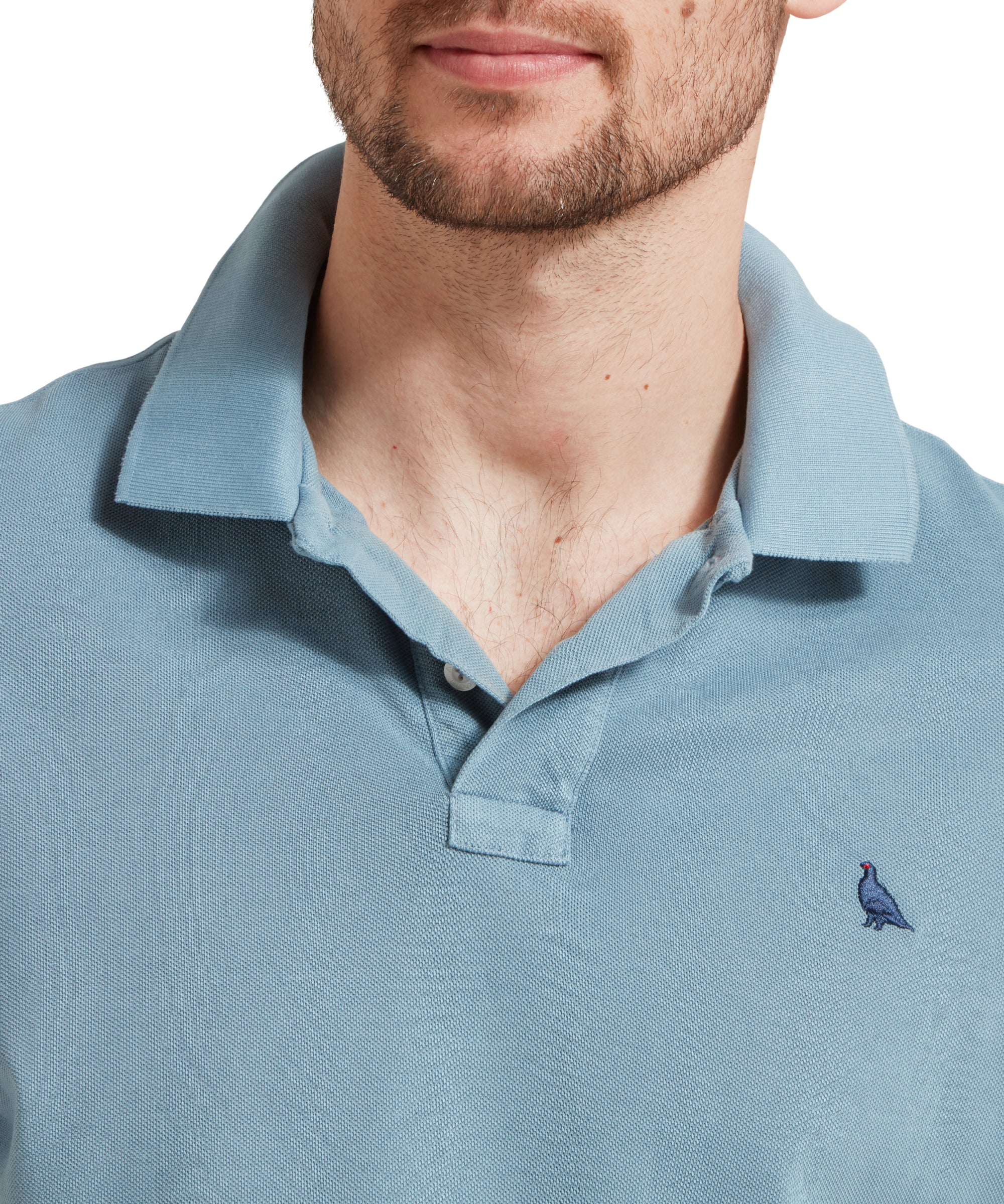 A close up image of a male model wearing a blue Schöffel polo shirt with a small embroidered bird logo on the chest. Image highlights the collar of the polo with 2 buttons.