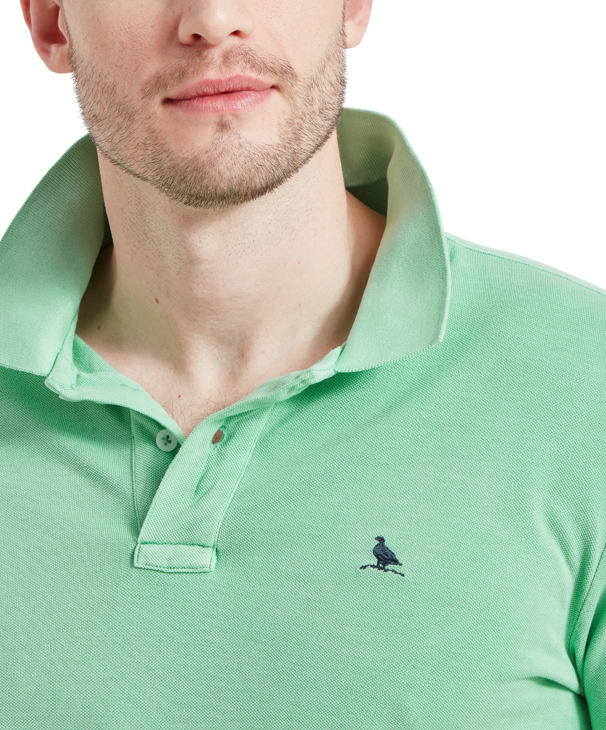 Close-up of the Schöffel St Ives Garment Dyed Polo Shirt for Men in Green with the collar popped up and the Ptarmigan embroidery on the right chest in navy thread.