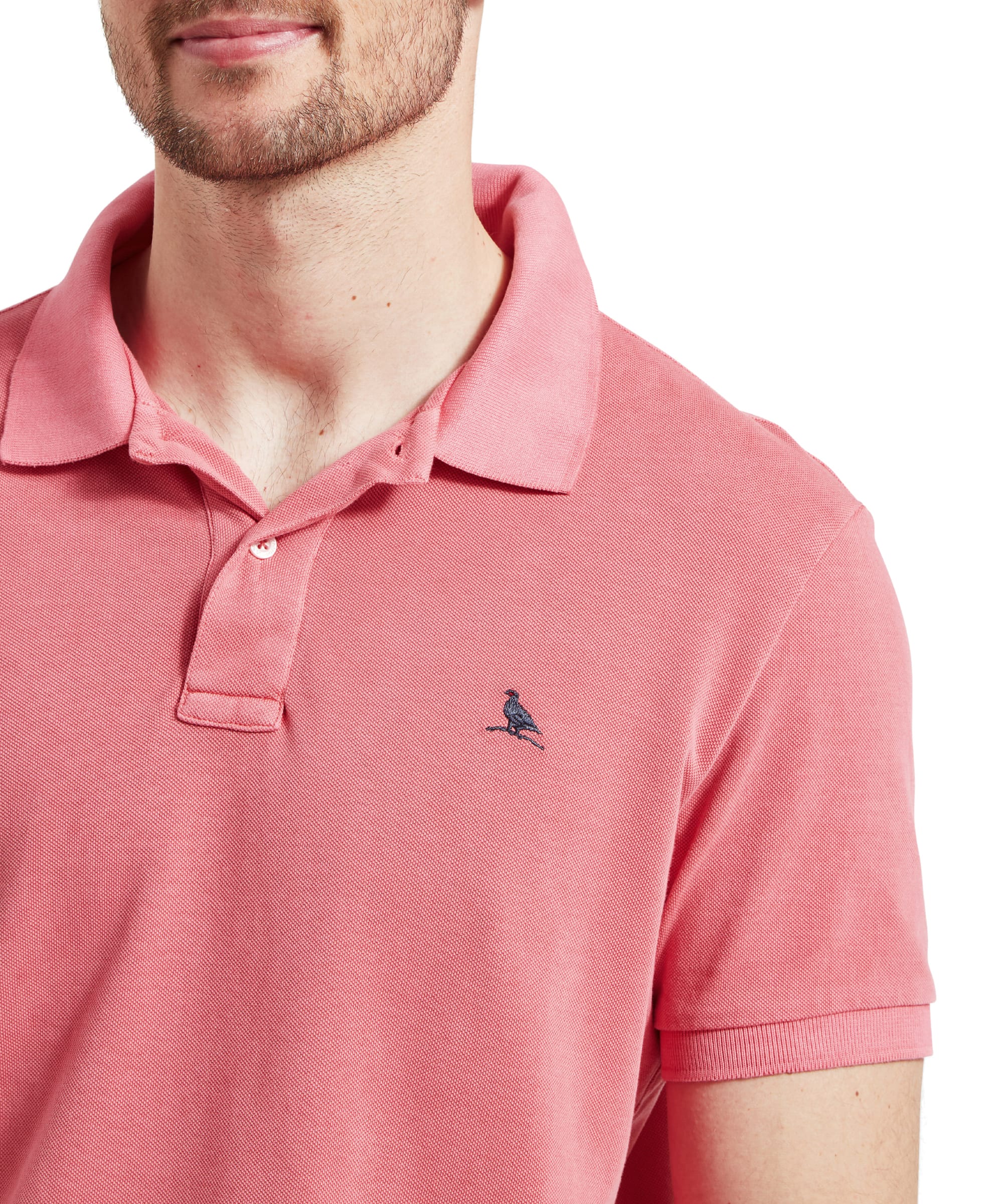 Close-up of the collar and chest area of the Schöffel St Ives Garment Dyed Polo Shirt for Men in Pink highlighting the navy embroidered Ptarmigan and the button placket of the collar.