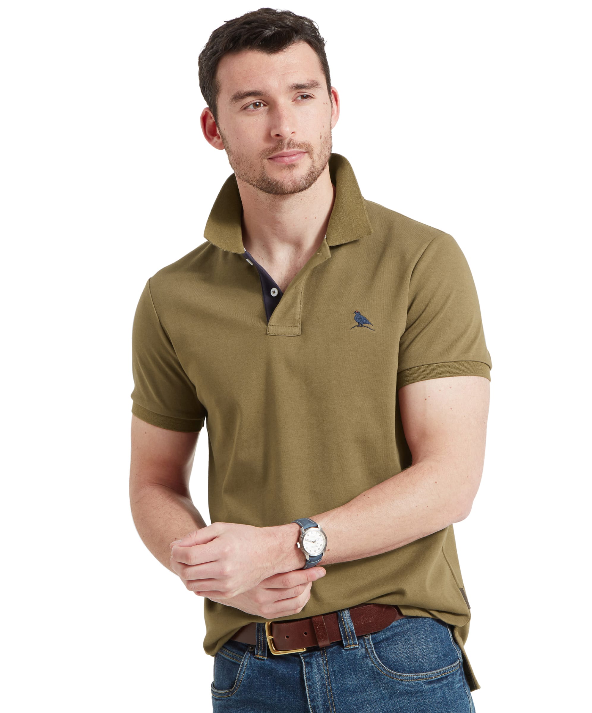 A man wearing the Schöffel Men's St Ives Jersey Polo Shirt in green, paired with blue jeans. The shirt features a small embroidered bird logo on the left chest and has a classic polo collar.