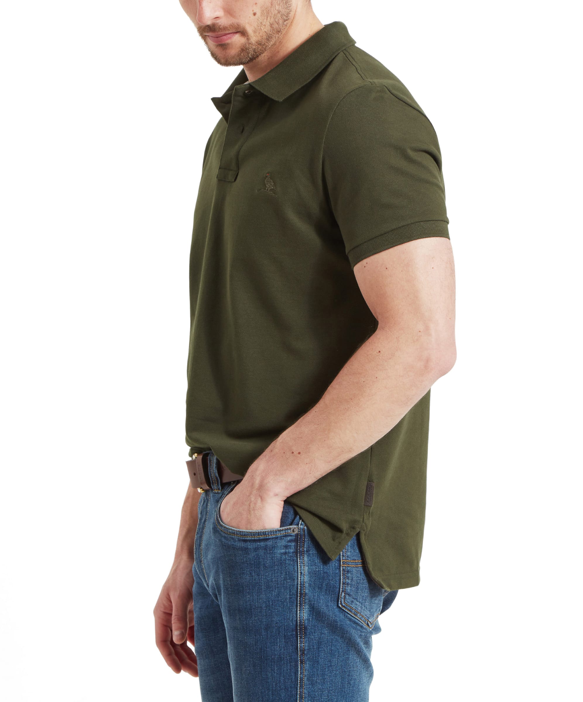 Side profile view of the man, highlighting the fit of the shirt, with the embroidered logo visible on the chest and the shirt neatly tucked into his jeans.