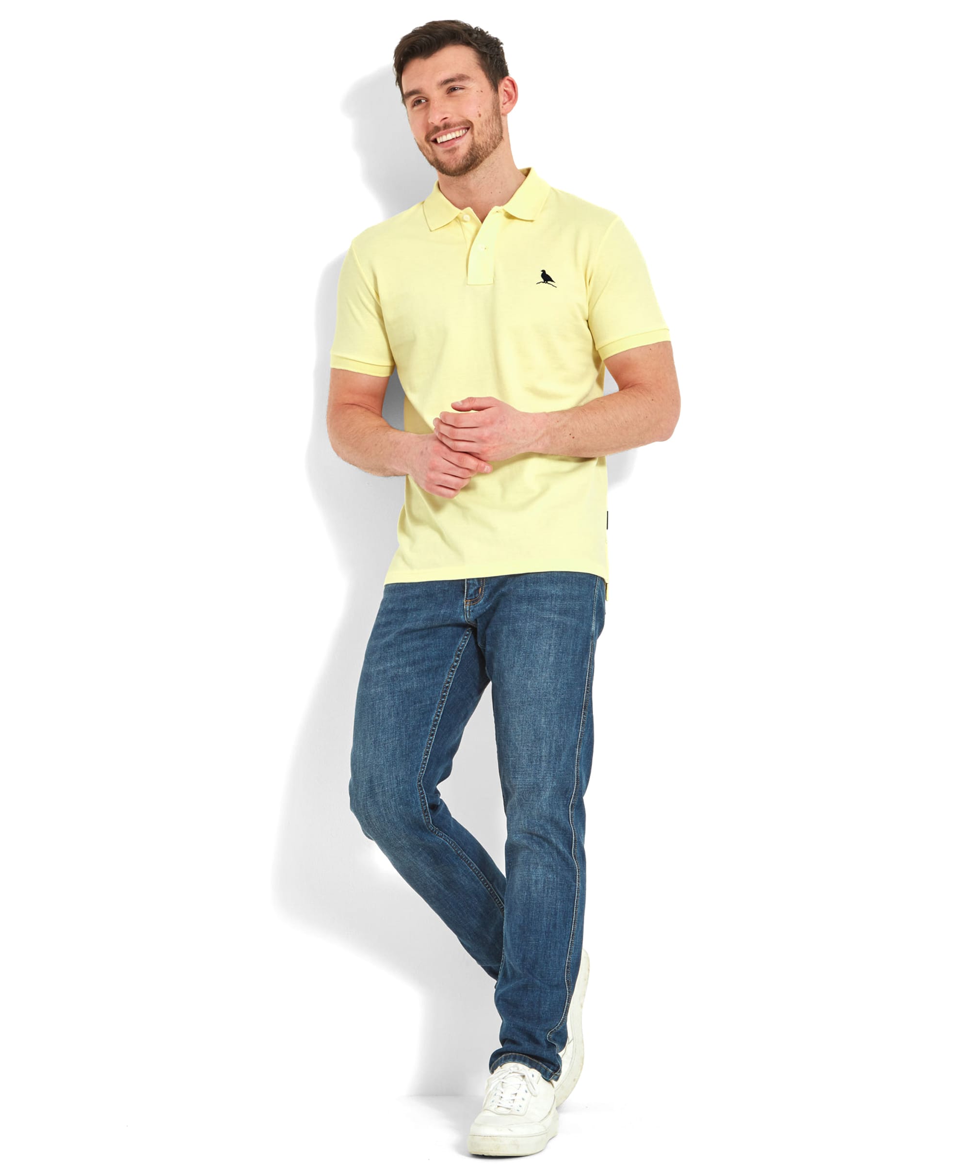 Full-body view of the man wearing the Schöffel St Ives Polo Shirt for Men in Light Yellow, standing casually with his hands clasped. The outfit includes white sneakers, enhancing the relaxed, casual look.