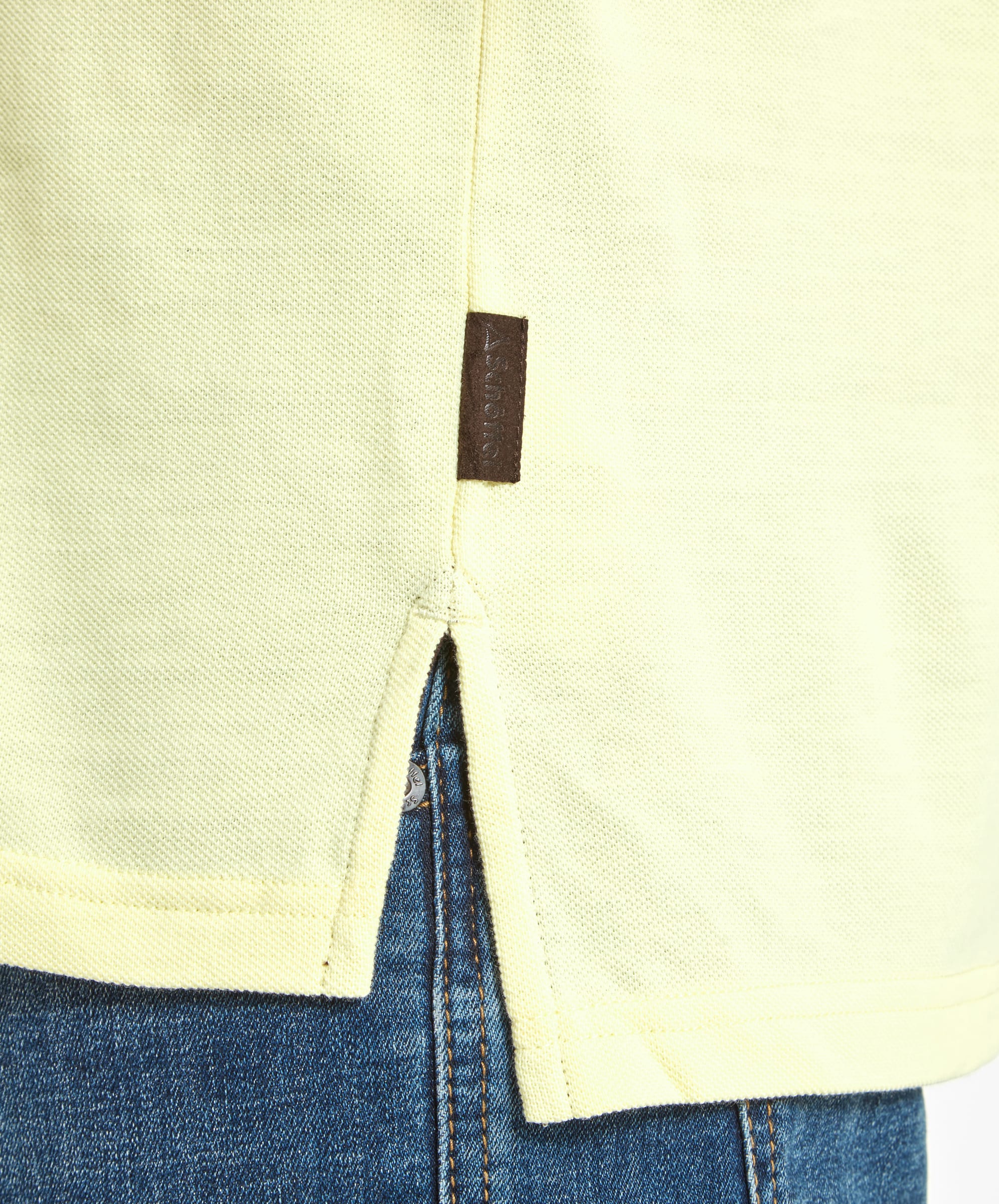 A detailed view of the Schöffel St Ives Polo Shirt for Men in Light Yellow's hem, showing a small tag and the side slit design, highlighting the quality and detailing of the garment.