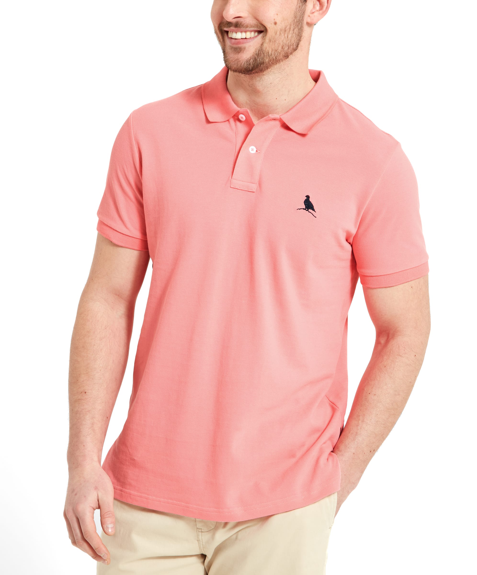 Front view of the man smiling, highlighting the casual and cheerful vibe of the outfit. The Schöffel St Ives Polo Shirt for Men in Pink is neatly worn, offering a fresh and vibrant look.