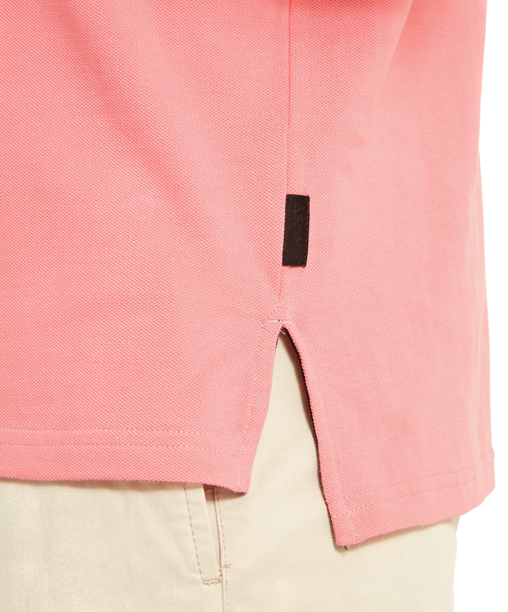 A detailed view of the Schöffel St Ives Polo Shirt for Men in Pink's hem, showing a small side slit and a tag, underlining the attention to detail and high-quality stitching of the garment.