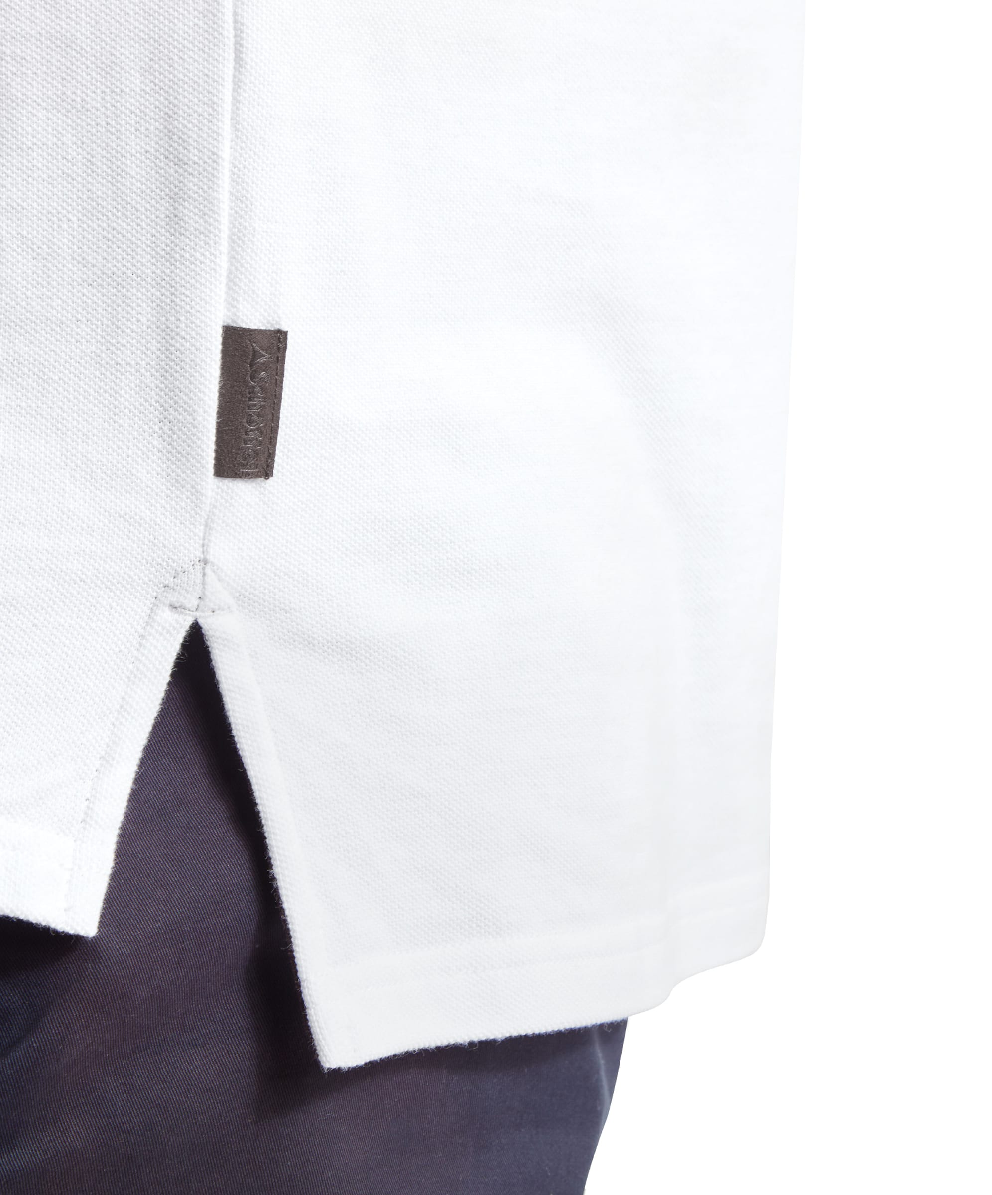 A close-up of the side vent and brand tag detail at the hem of the Schöffel St Ives Polo Shirt for Men in White.