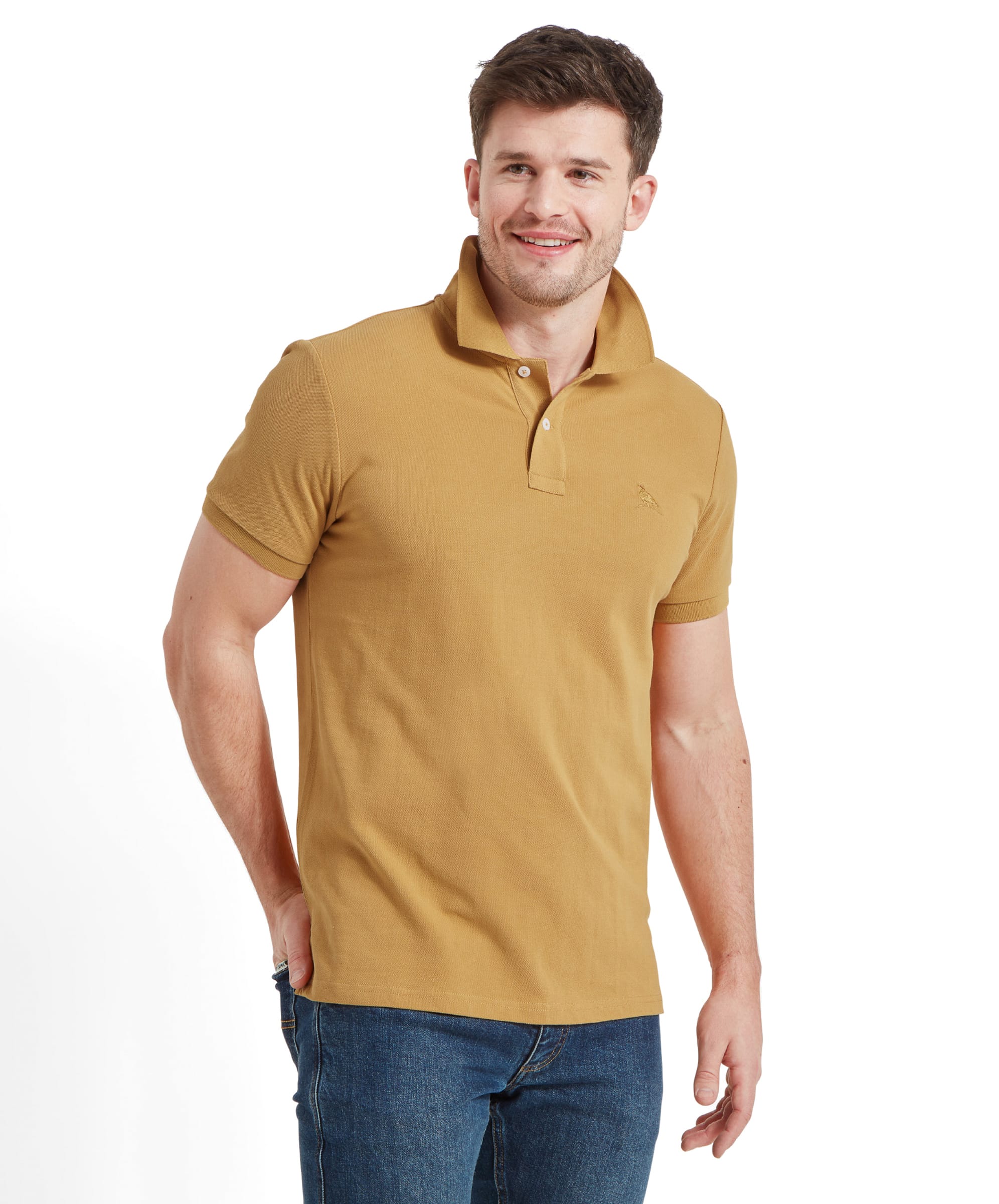 A man wearing a Schöffel St Ives Polo Shirt for Men in Yellow with a subtle embroidered bird logo on the chest, paired with blue jeans. He has short brown hair and is smiling, standing in a relaxed pose with hands in his pockets.