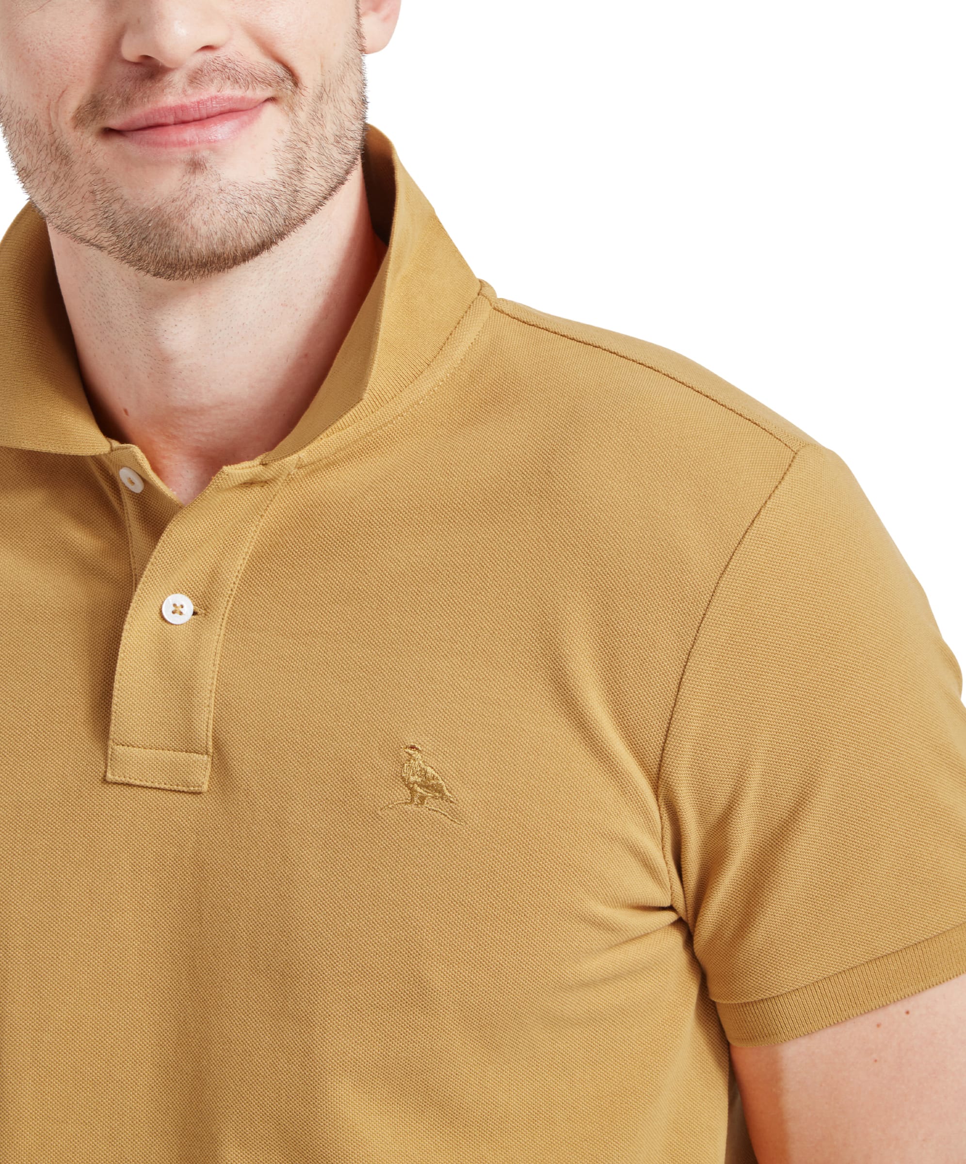 A close-up of the Schöffel St Ives Polo Shirt for Men in Yellow’s chest area, showcasing the small embroidered bird logo in matching color.