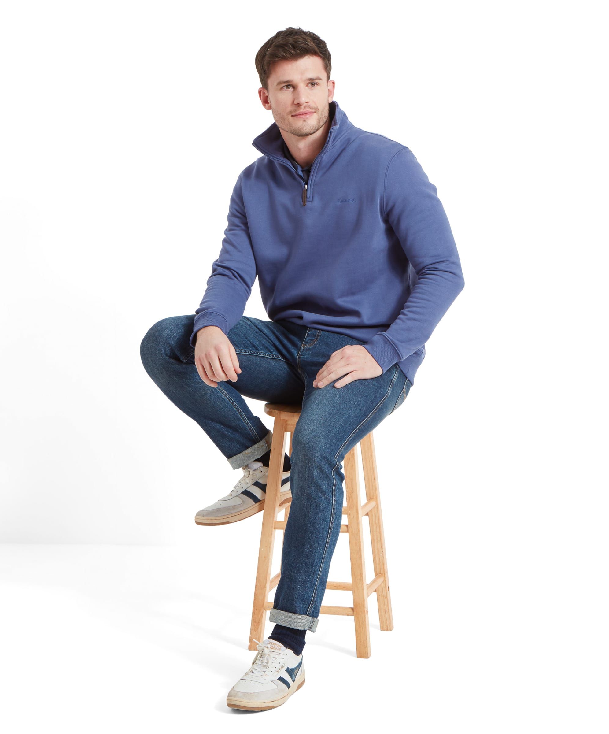 In another shot, the man is seated with a slightly different angle, showing more of the Schöffel St Merryn Sweatshirt for Men in Light Blue's front and its soft texture. The light blue color stands out, creating a fresh and clean look.