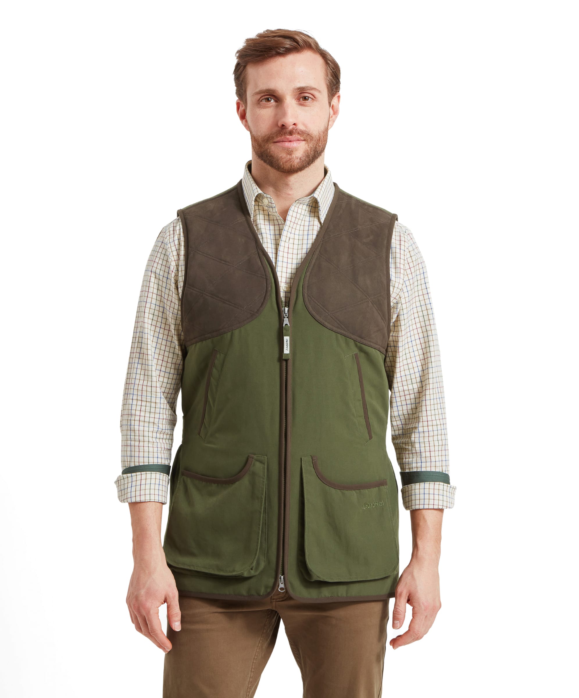 A man stands modelling the Schöffel Stamford Vest II for Men in Green with a check shirt and brown trousers. He stands with his hands casually to his sides and the shirt sleeves rolled up slightly.