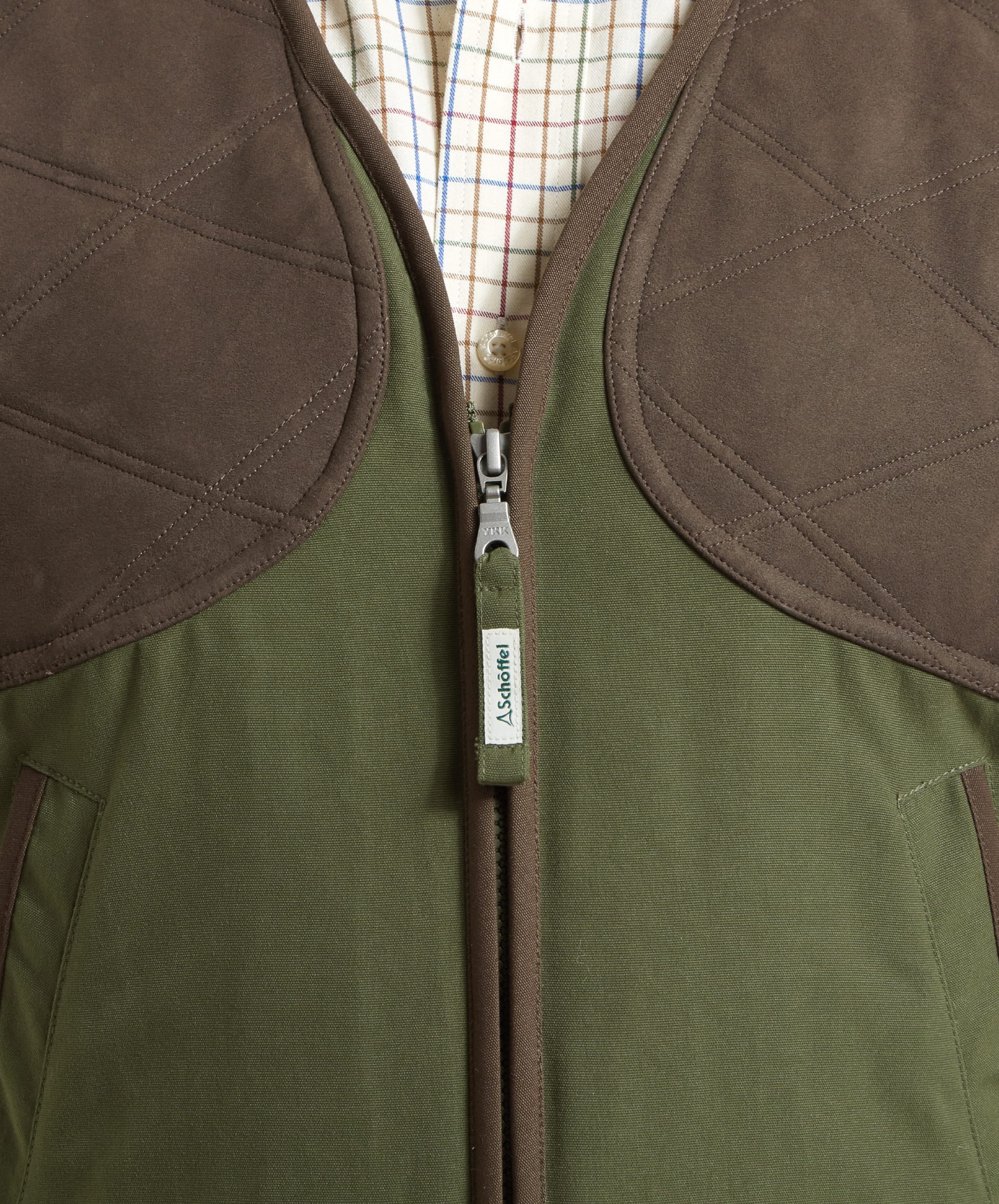 Close-up of the front zip on the Schöffel Stamford Vest II for Men in Green highlighting the branded zip pull, the quilted chest sections and canvas material of the vest.