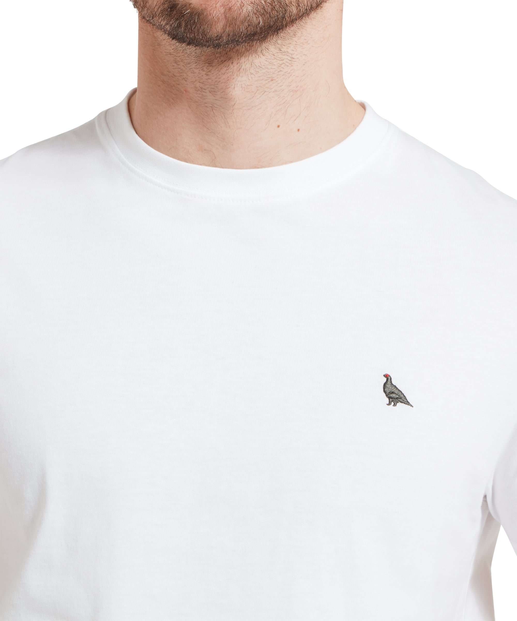 A close-up of a man wearing a white t-shirt featuring a small embroidered bird design on the left side of the chest.