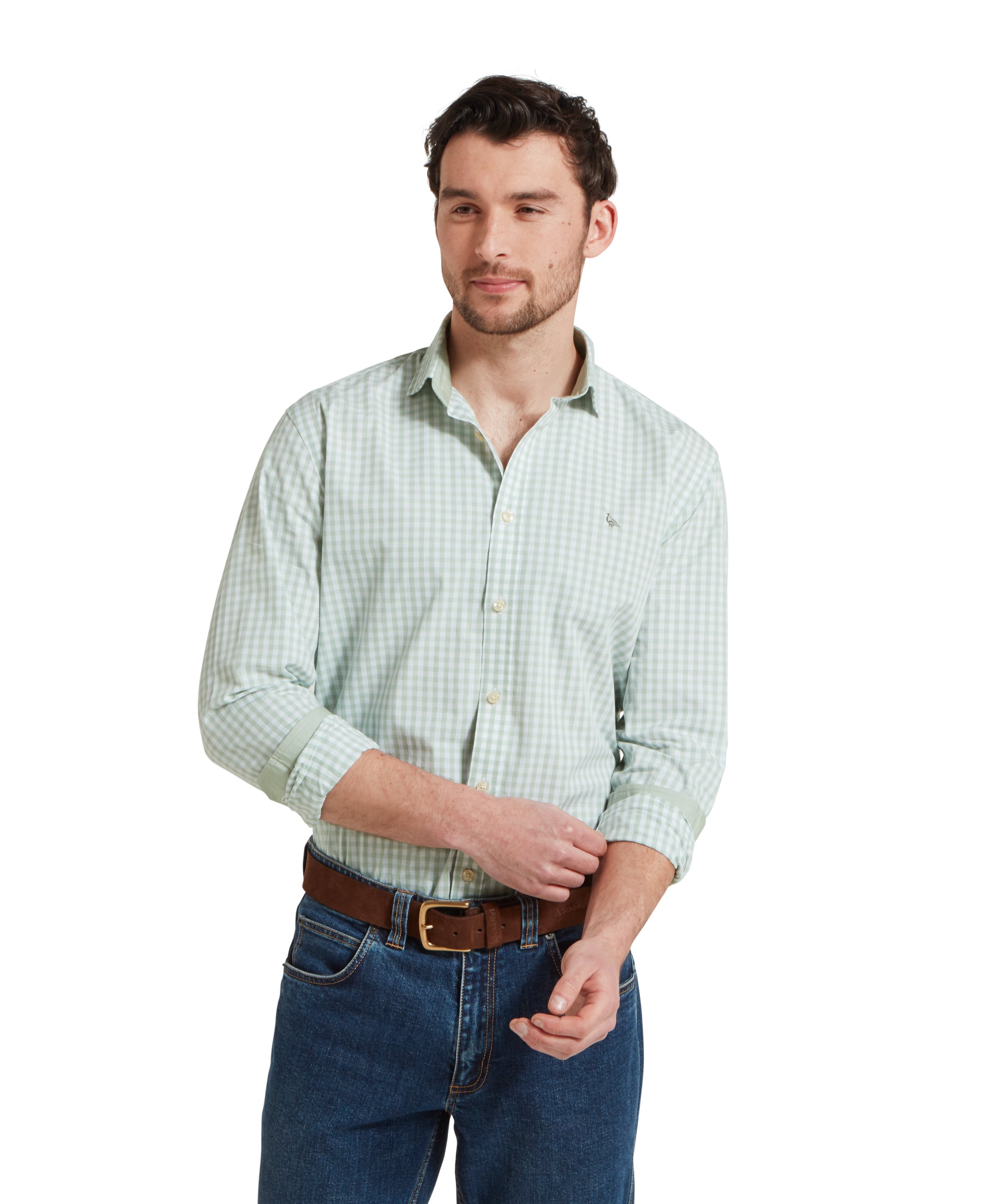 A man is wearing a Schöffel Thorpeness Tailored Shirt for Men in Green with the sleeves rolled up. The shirt is paired with dark jeans.