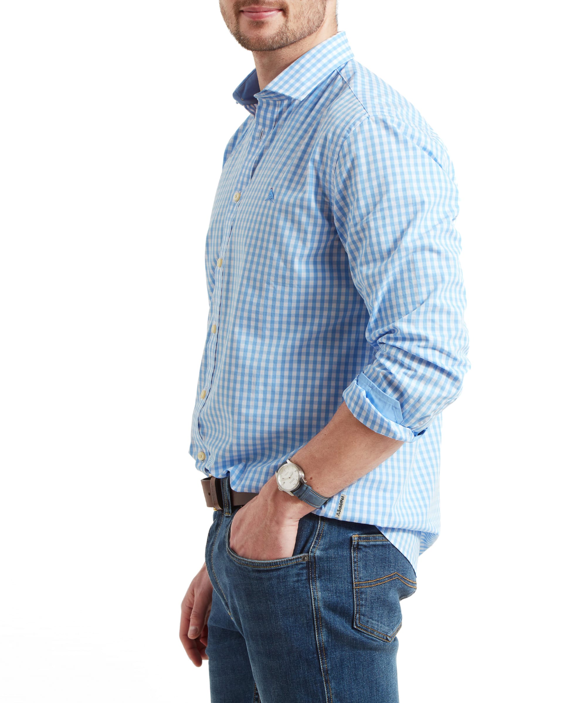 A side view of the man wearing the Schöffel Thorpeness Tailored Shirt for Men in Blue, highlighting the shirt's tailored fit and details. His hands are in his pockets, and a watch is visible on his left wrist.