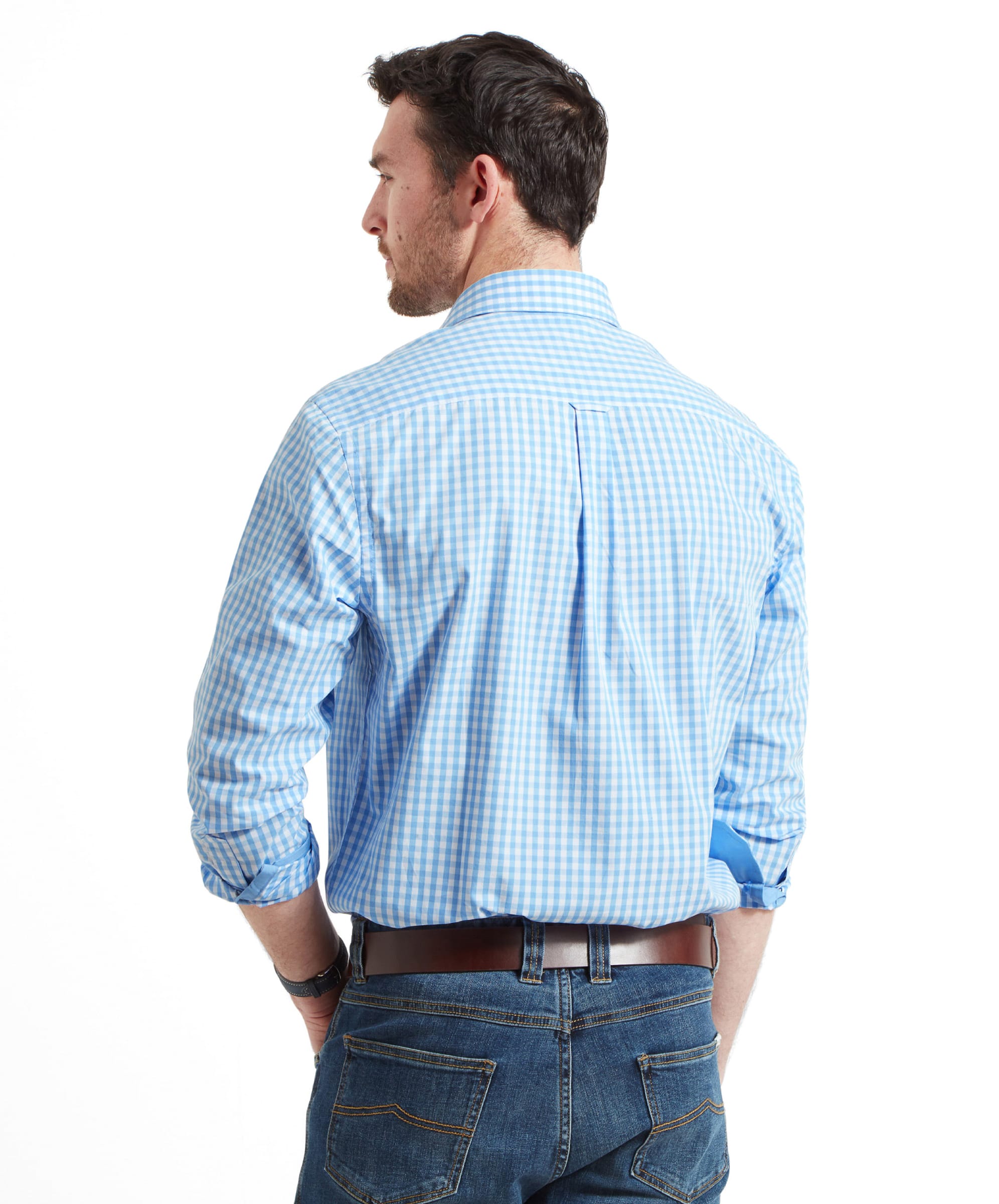 A back view of the man in the Schöffel Thorpeness Tailored Shirt for Men in Blue, showing the shirt's fit and pleat detail at the back, paired with jeans.