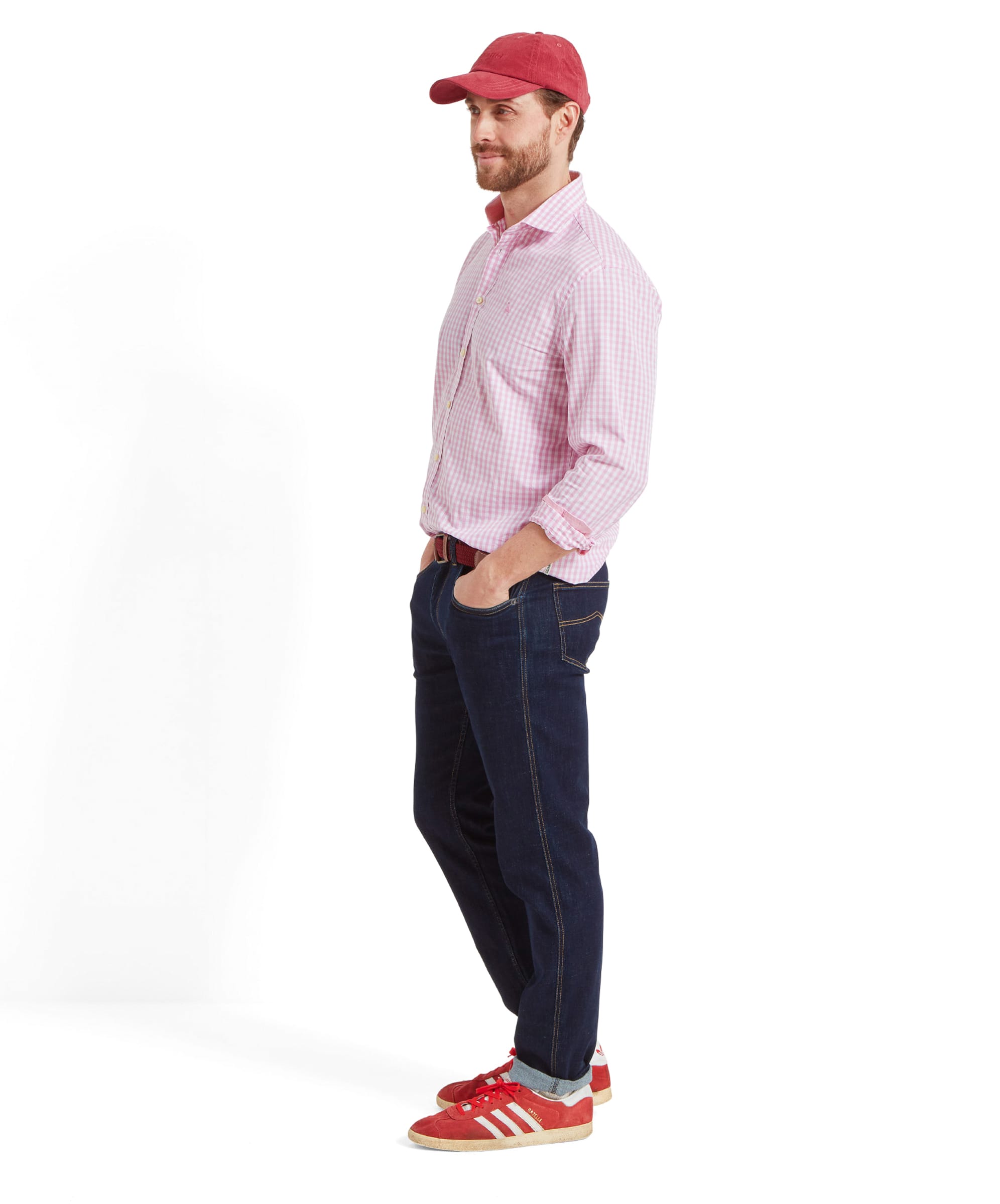 A side profile of the man in the Schöffel Thorpeness Tailored Shirt for Men in Pink, showing the shirt's classic fit and detailing. The red cap adds a sporty touch to the look.