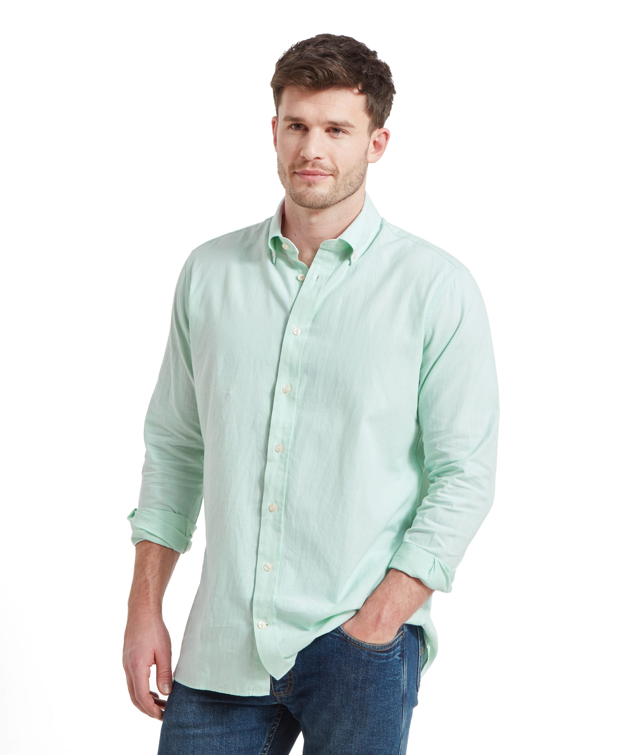 A man wearing a Schöffel Titchwell Tailored Shirt for Men in Green with rolled-up sleeves. He stands with a relaxed posture, hands in pockets, against a white background, looking forward with a slight smile.