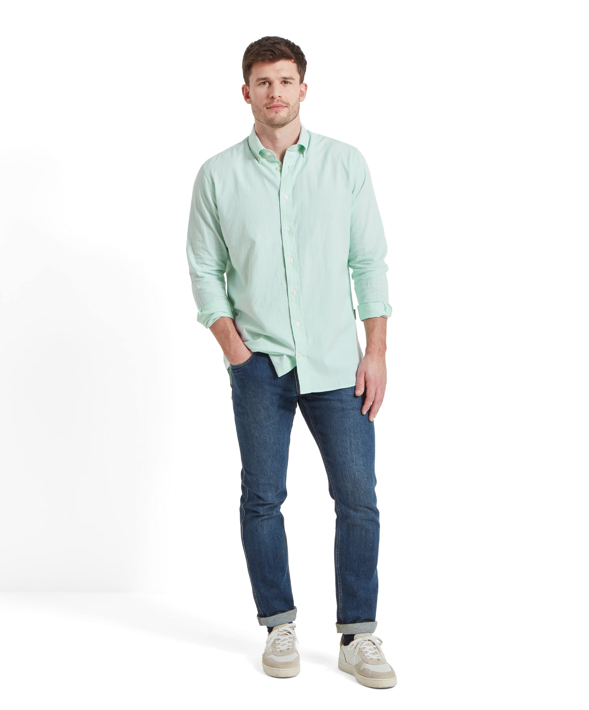 The same man is standing in a full-length pose, wearing the Schöffel Titchwell Tailored Shirt for Men in Green, blue jeans, and light-colored sneakers. He looks directly at the camera with a neutral expression.