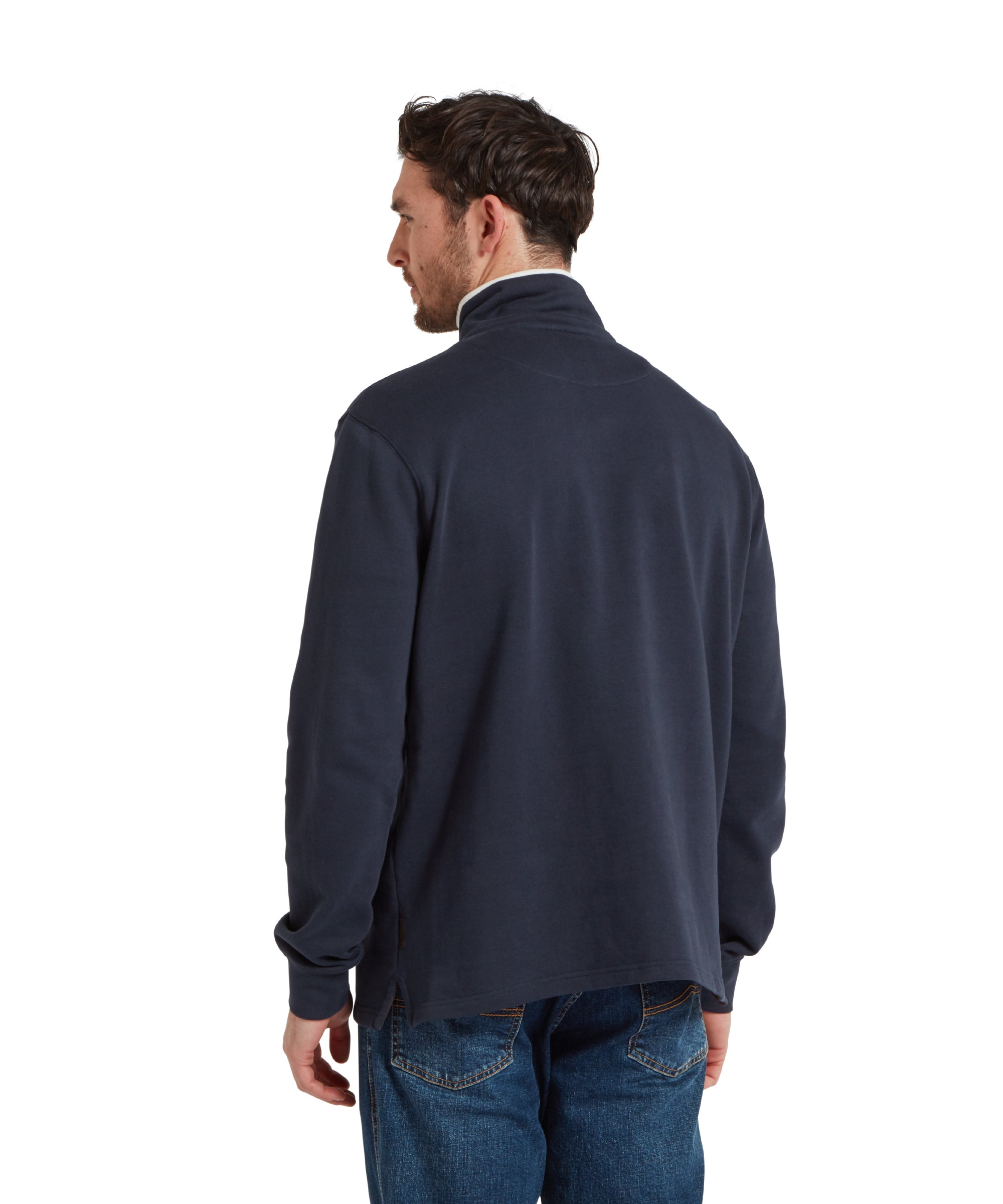 Back image of a male model wearing a blue Schöffel sweatshirt with a white stripe with blue large embroidered Schöffel logo across the chest. It is paired with a white t-shirt and dark blue jeans and he is standing in a relaxed pose with his hands by his side.