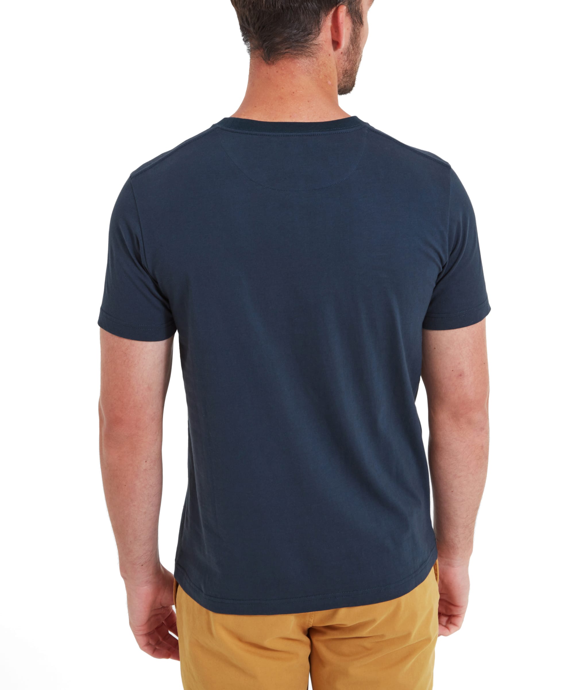 The man is shown from the back, wearing a Schöffel Trevone T-Shirt for Men in Navy and mustard yellow shorts, hands in pockets.