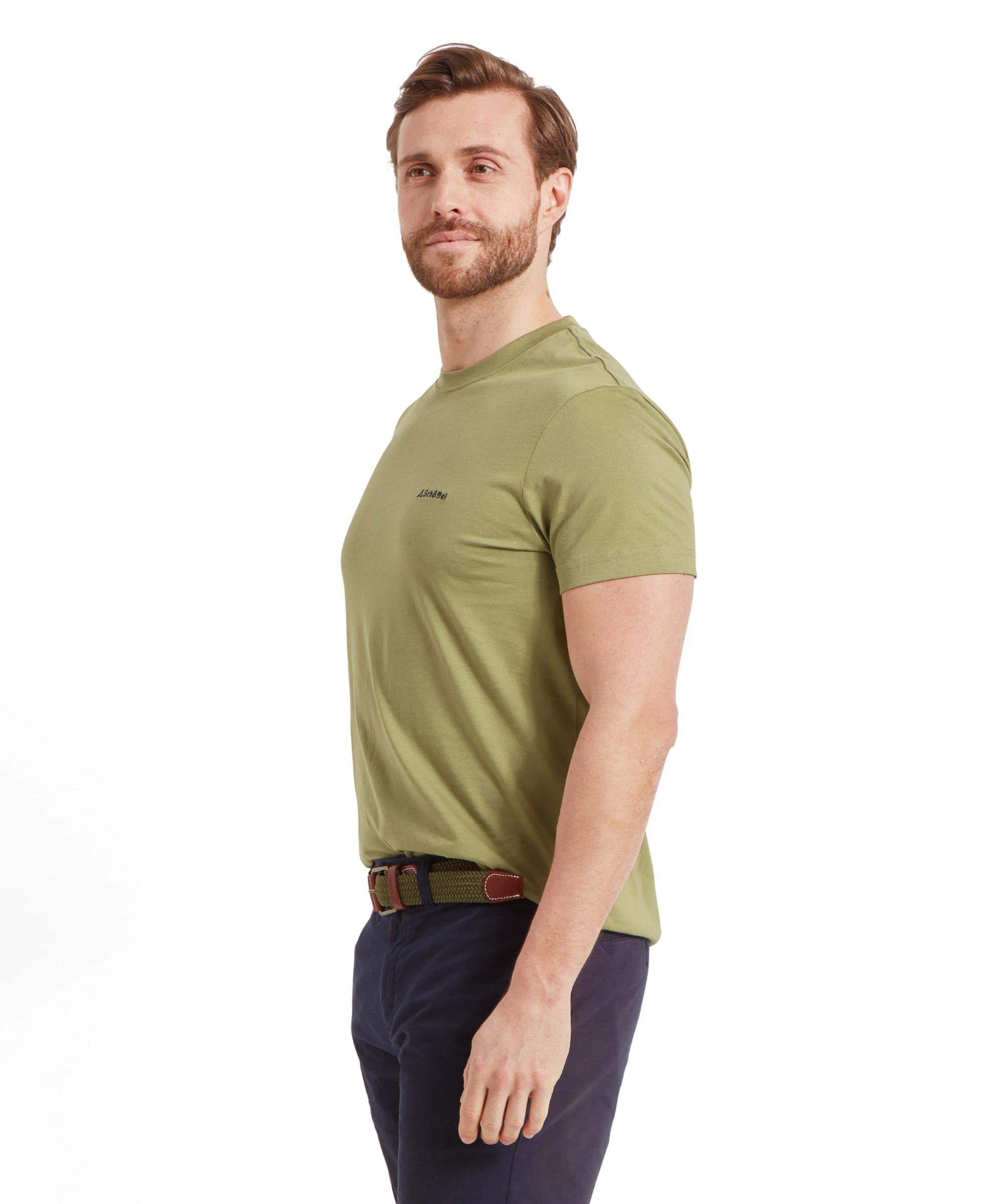 In a side profile view, the man shows off the fit of the Schöffel Trevone T-Shirt for Men in Olive Green. His posture is straight, and his expression is neutral. The image focuses on the fit of the T-shirt around the shoulders and torso.