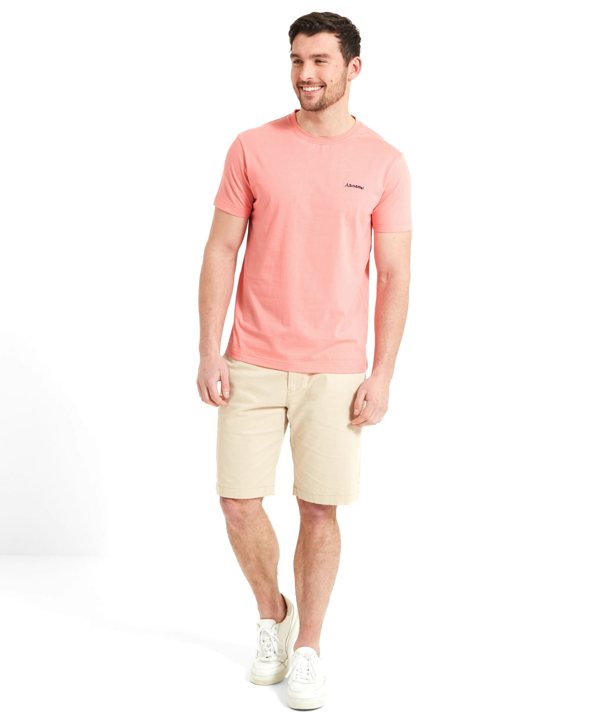 The same man in the Schöffel Trevone T-Shirt for Men in Pink and beige shorts, smiling, and looking slightly to his right, with hands by his sides.