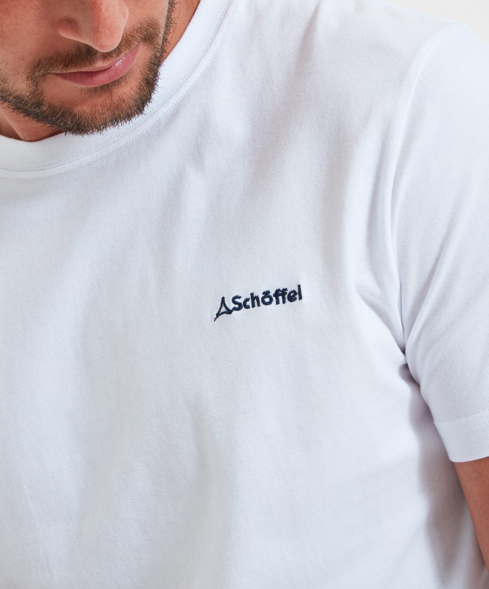 Close-up of the small embroidered "Schöffel" logo on the Schöffel Trevone T-Shirt for Men in White.