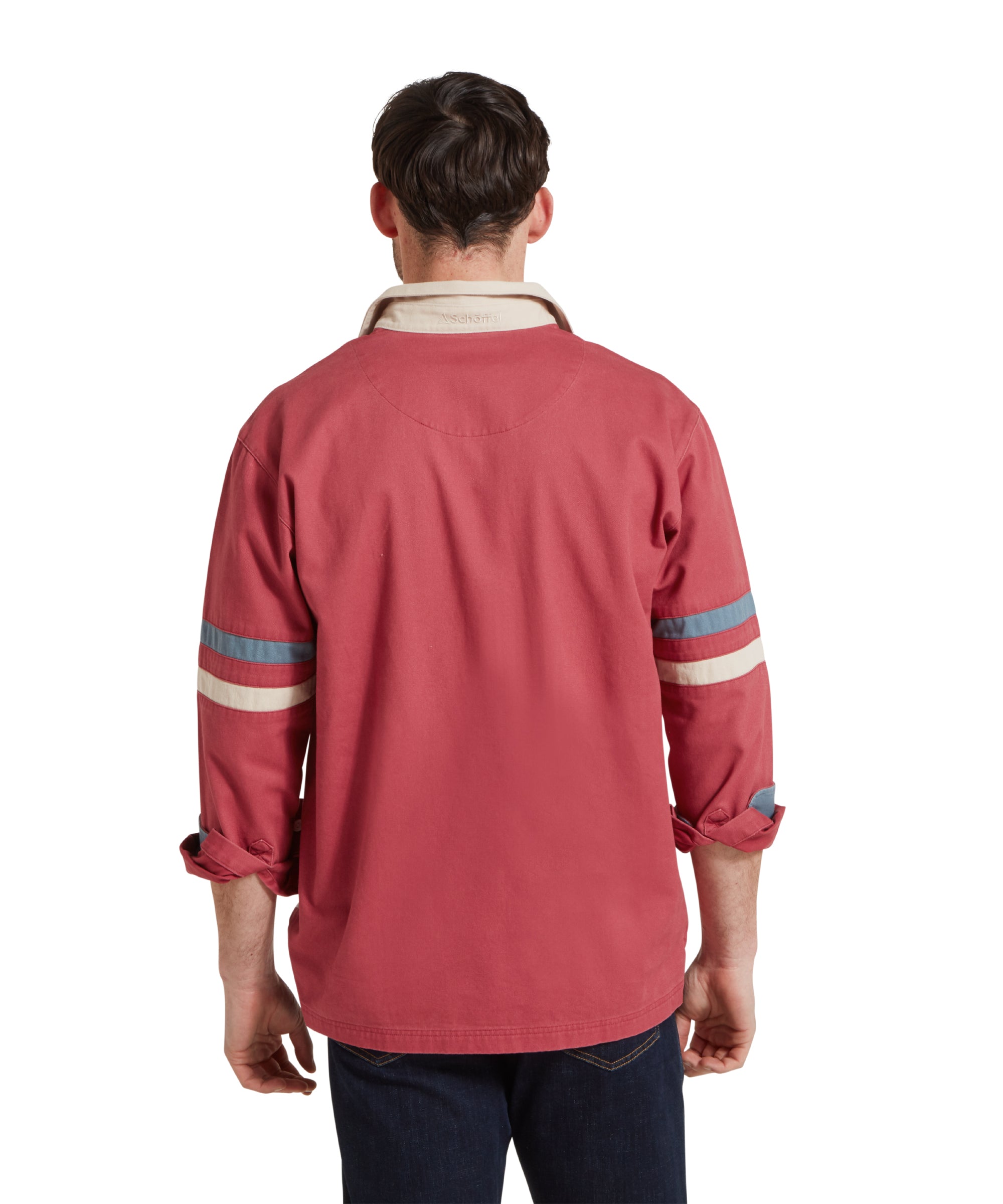 A back image of a male model wearing a red Schöffel deck shirt with blue and beige stripes on the arms. It is paired with dark denim jeans, blue polo shirt, beige belt and navy trainers. He is standing in a relaxed pose with his arms by his side.