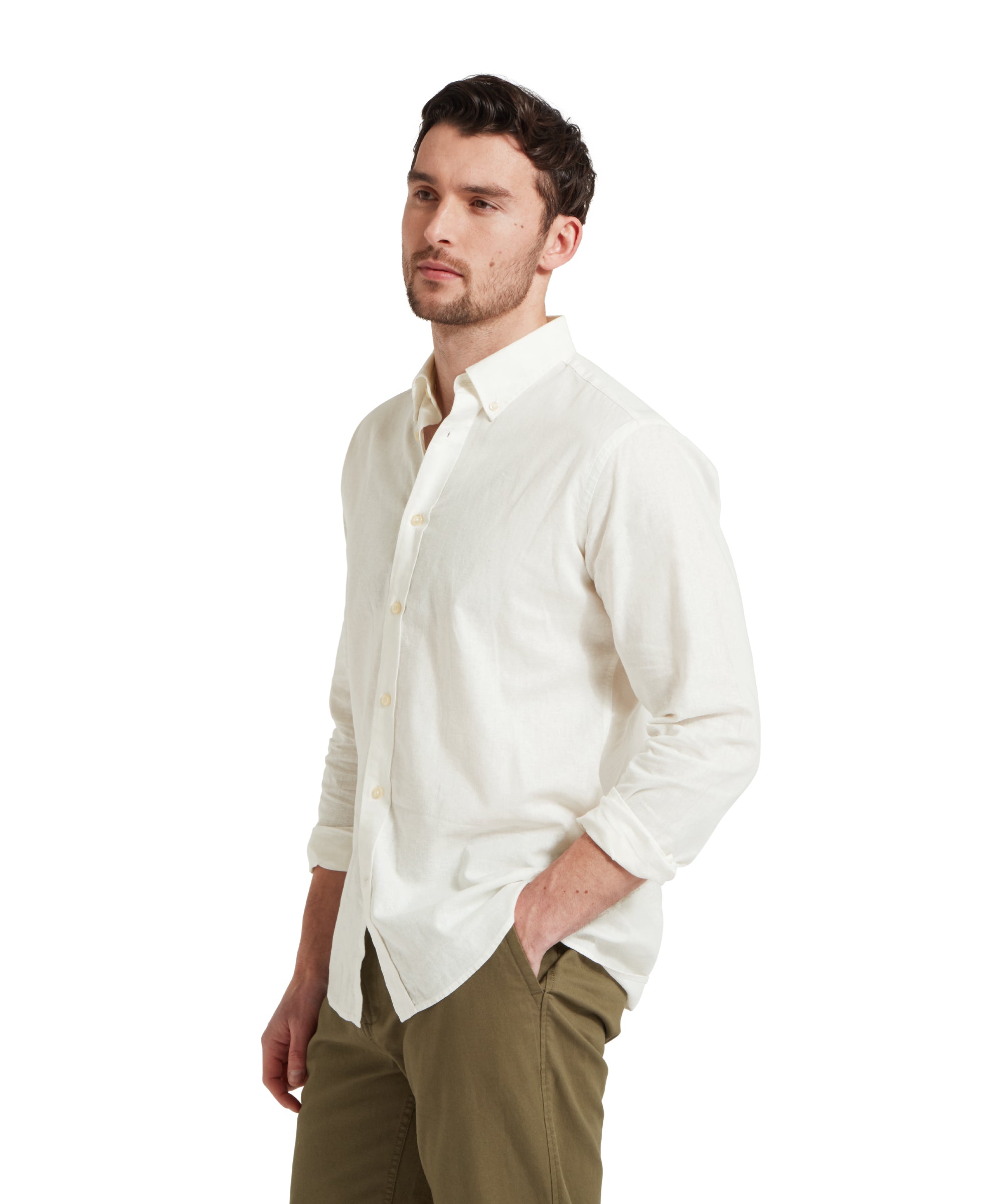 Side profile of a male model wearing a white Schöffel shirt paired with dark green chinos trousers. He is standing in a relaxed pose with one hand in his pocket.