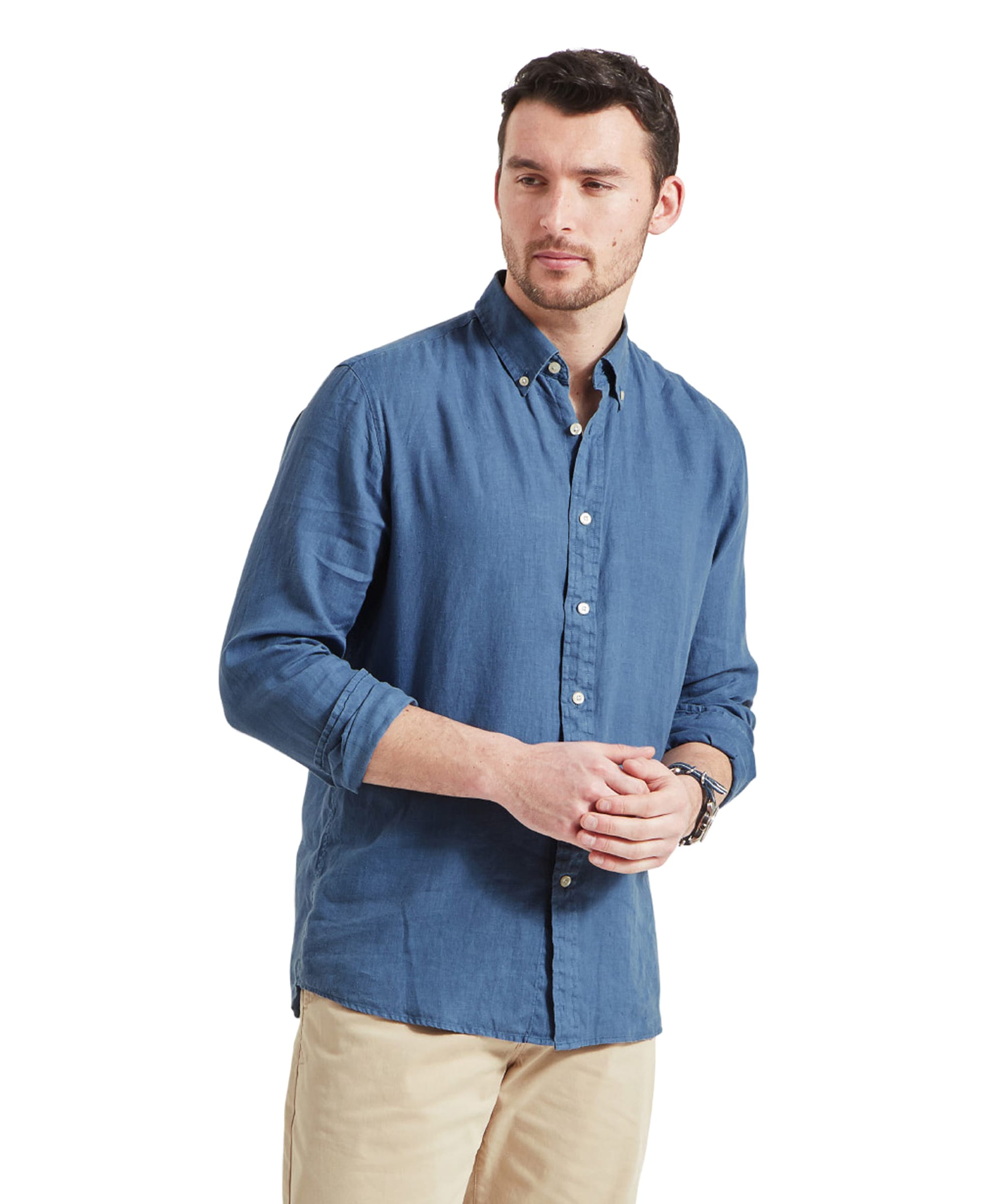 A man wearing a Schöffel Walsingham Linen Shirt for Men in Blue with long sleeves, buttoned up and tucked into beige shorts. He stands confidently, with a casual yet polished look.