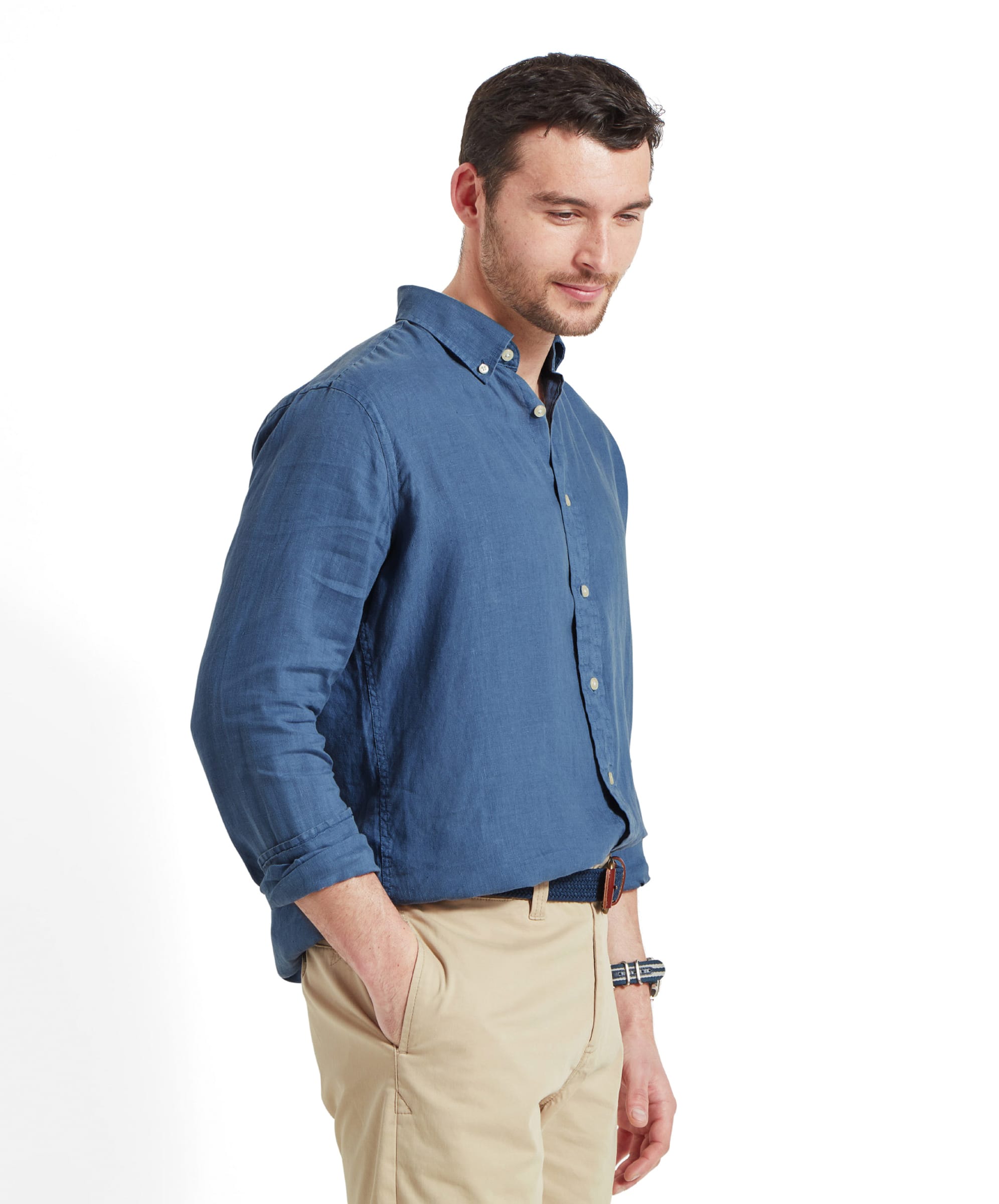 A side view of the man in the Schöffel Walsingham Linen Shirt for Men in Blue and beige trousers, his hands in his pockets. The shirt's soft texture and comfortable fit are evident.