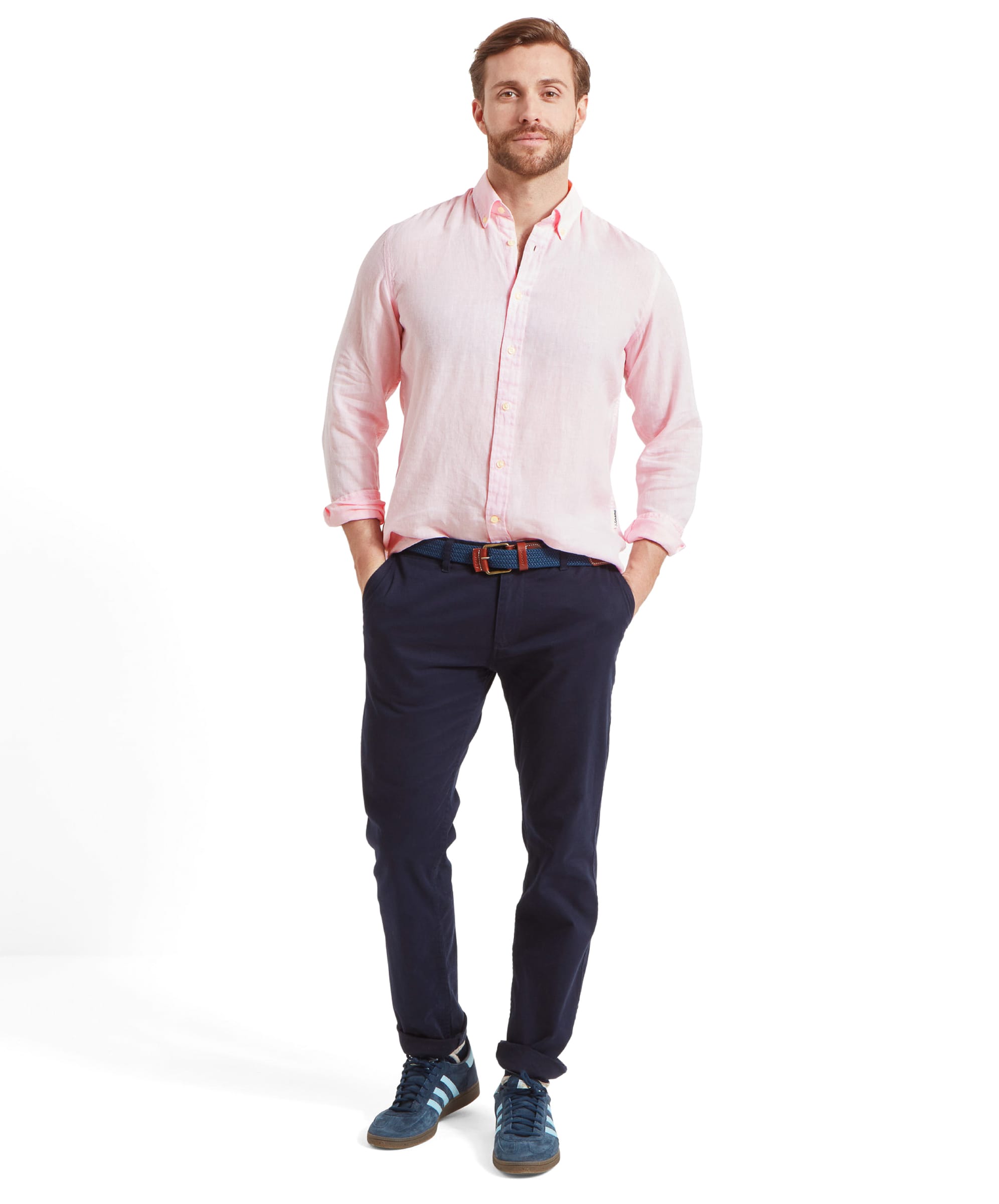 The same man is shown in a full-body shot, wearing the Schöffel Walsingham Linen Shirt for Men in Pink paired with dark navy trousers and blue trainers. He is standing with a relaxed posture, hands in his pockets, highlighting a casual yet polished look suitable for a laid-back summer day.