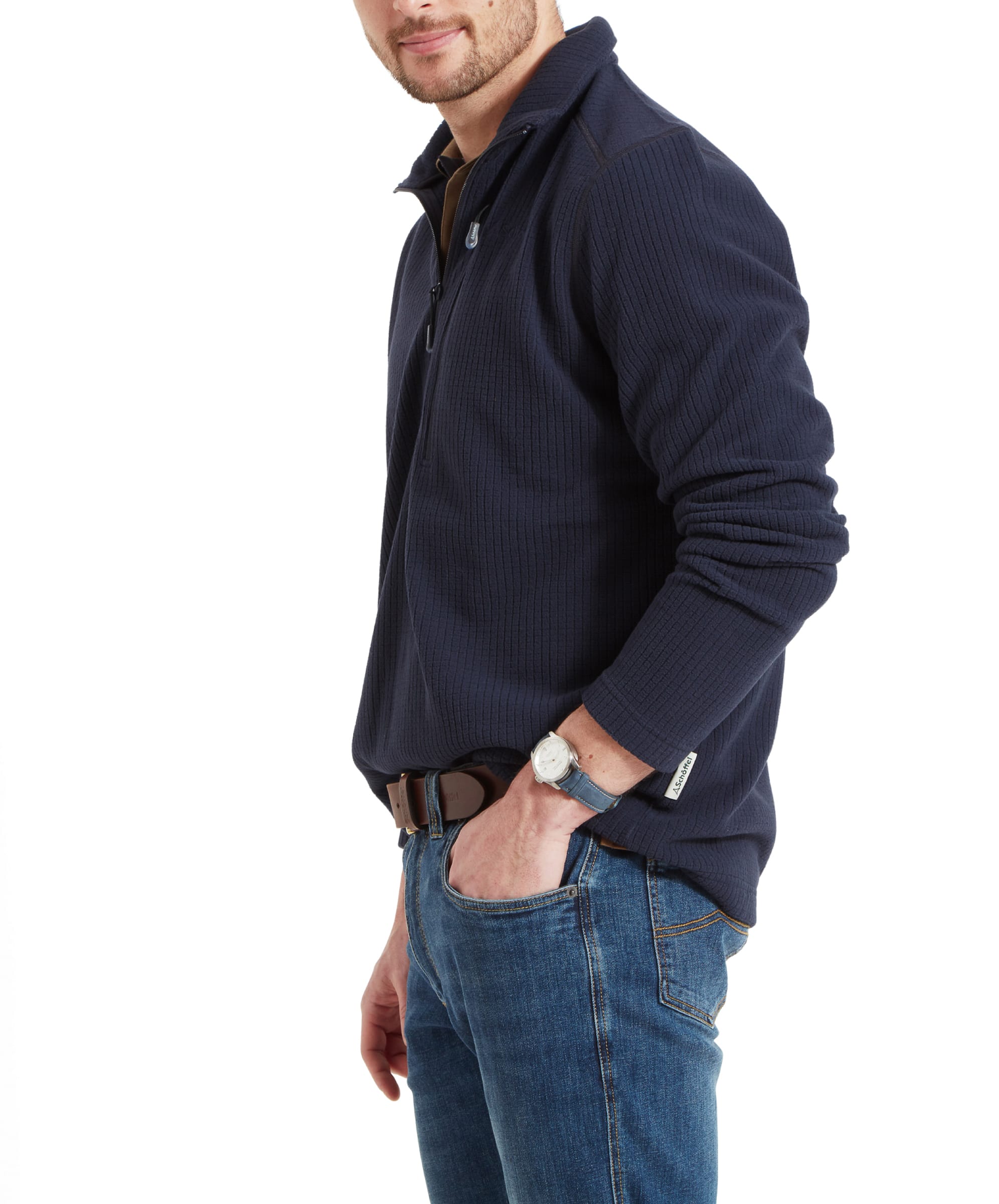 The male model is shown in a side profile, wearing the same Schöffel Welland Lightweight Fleece for Men in Blue with a half-zip. The ribbed texture of the fleece is visible, and it is paired with blue jeans. The model's casual stance and neutral expression convey a laid-back style.