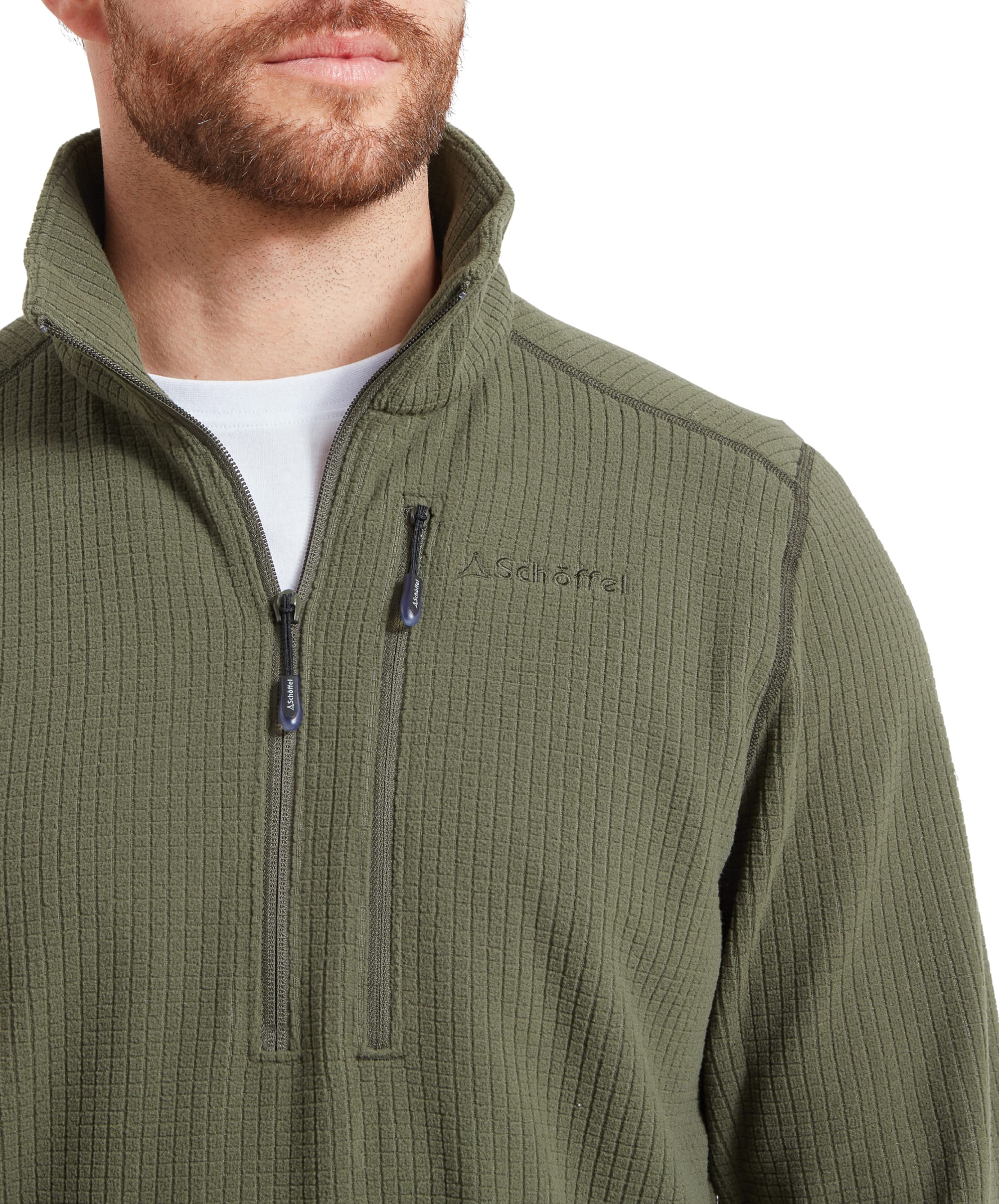 The image zooms in on the chest pocket area of the Schöffel Welland Lightweight Fleece for Men in Green, showing the fine details and the quality of the zipper. The texture of the fabric is clearly visible.