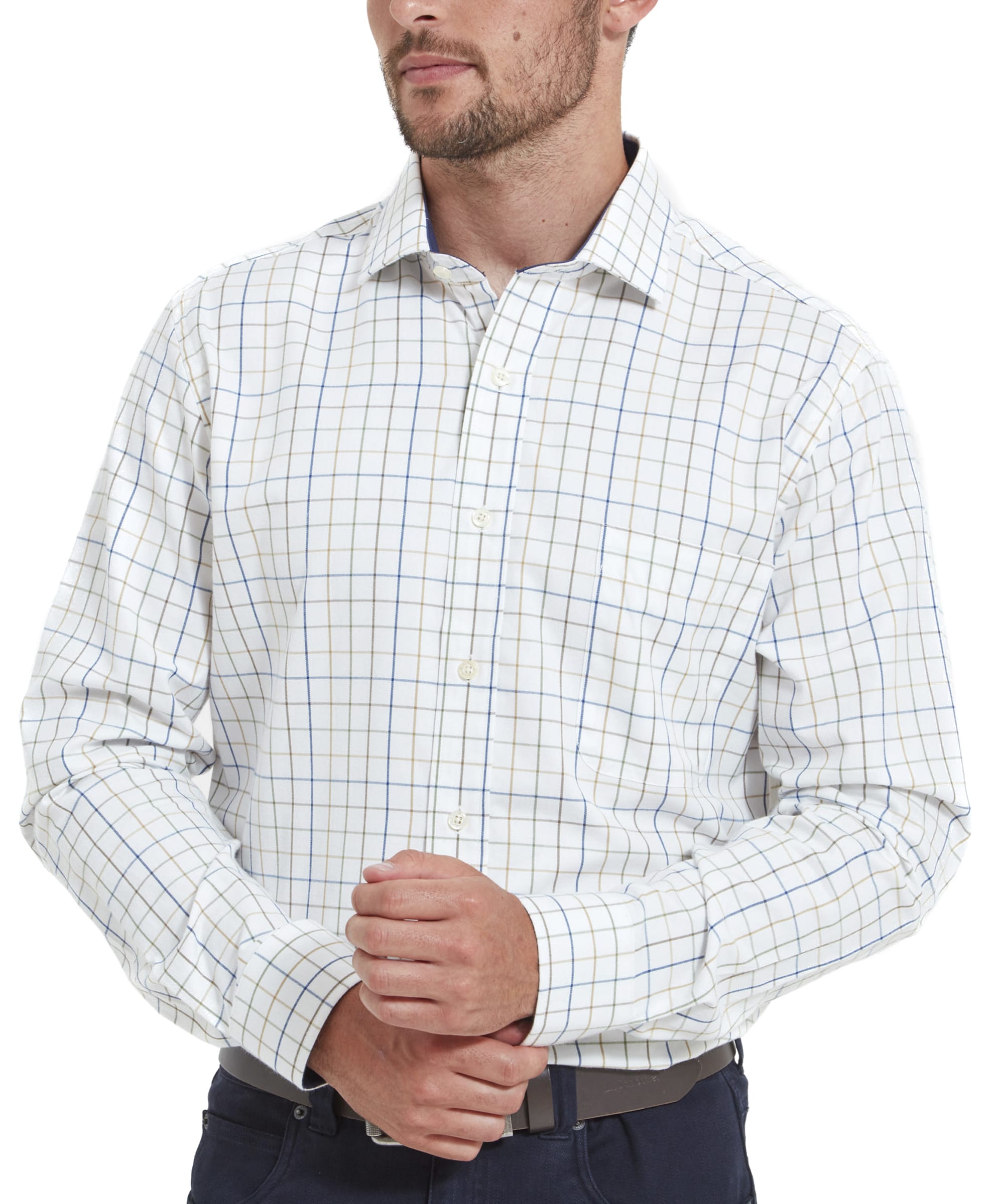 A close-up front view of a man wearing a Schöffel Wells Tailored Shirt for Men in Green with a subtle check pattern in blue, green, and tan. The shirt features a classic collar and long sleeves with buttoned cuffs. The man’s hands are folded in front of him, showcasing the shirt’s crisp structure. The shirt is tucked into dark navy trousers.