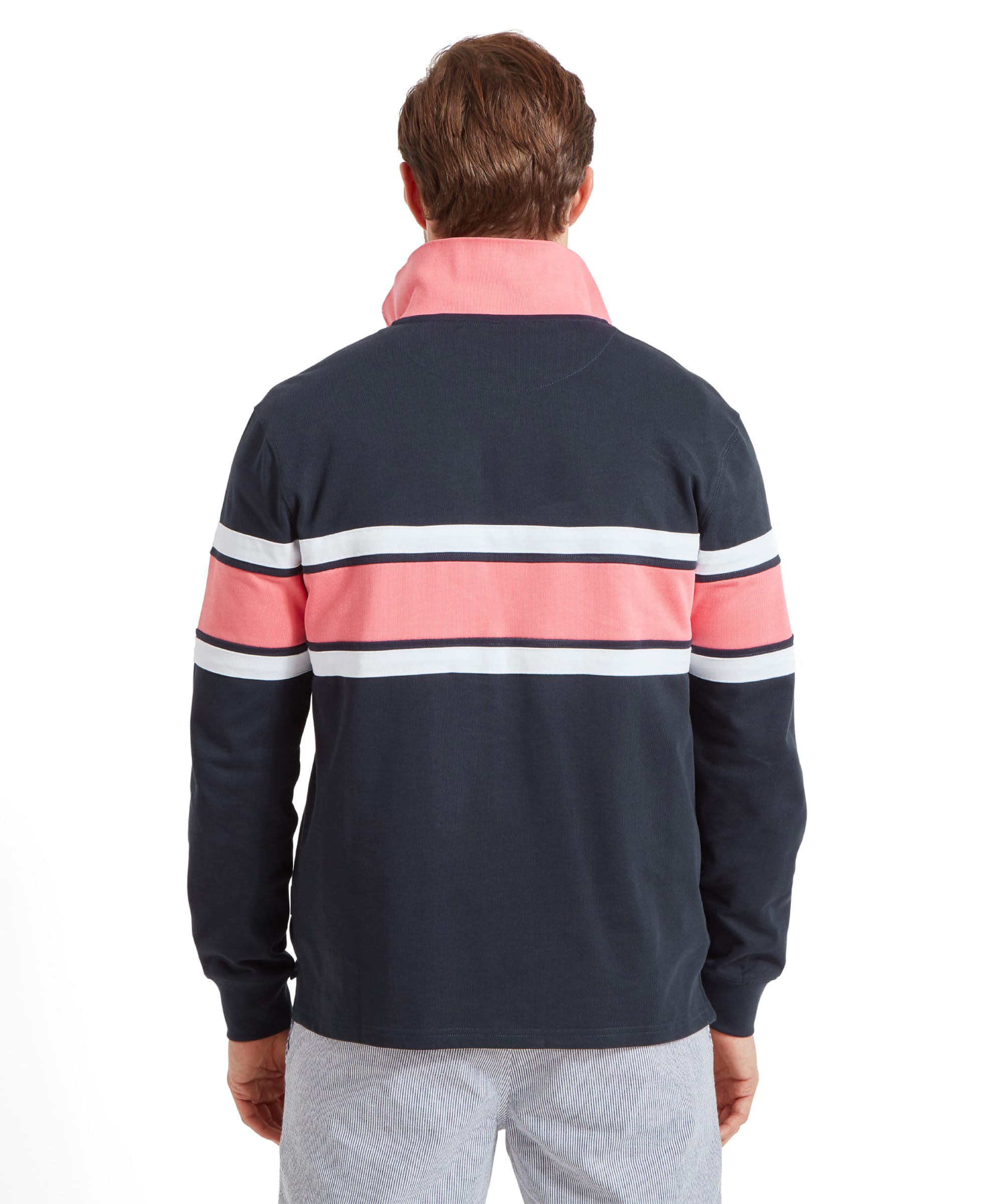 Back view of the man wearing the Schöffel Exmouth Heritage 1/4 Zip for Unisex in Navy. The sweatshirt has two horizontal pink stripes and white borders across the back.