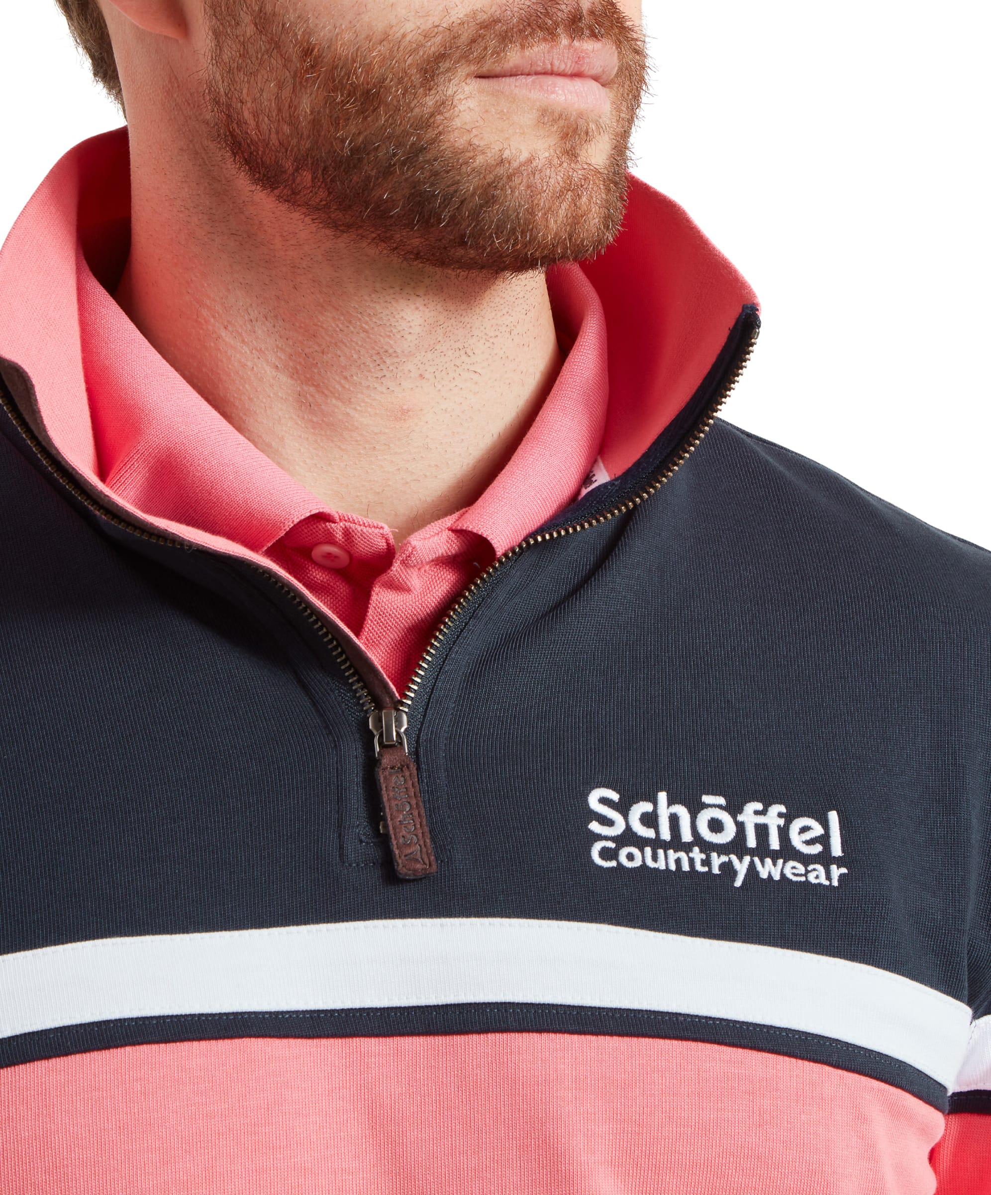 Close-up of the man’s upper chest and collar on the Schöffel Exmouth Heritage 1/4 Zip for Unisex in Navy, showing the "Schöffel Countrywear" logo on the left side of the chest and the pink collar turned up.