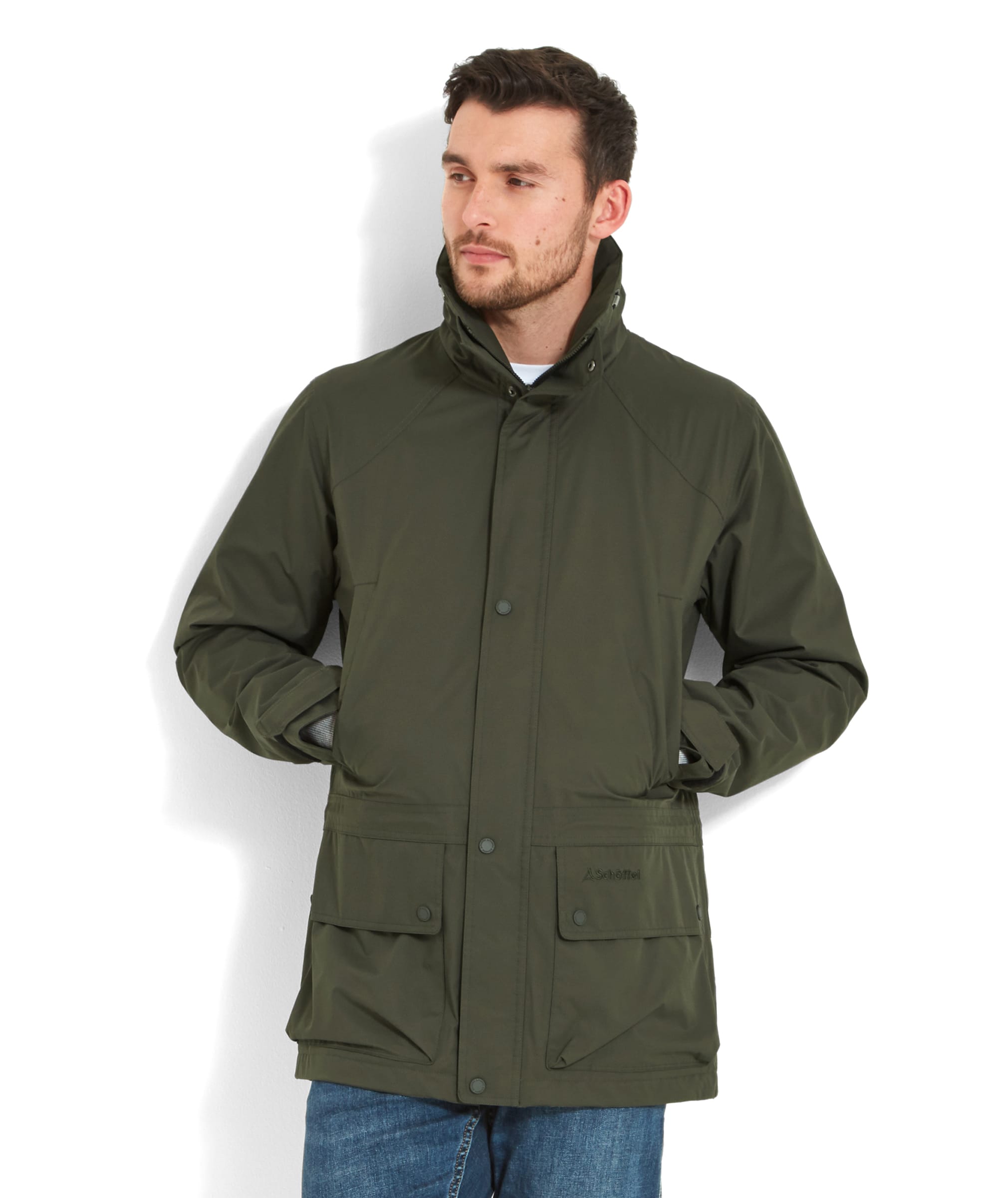 A man wearing a Schöffel Unisex Ketton Jacket II in Green, standing with his hands in his pockets, looking slightly to the side.