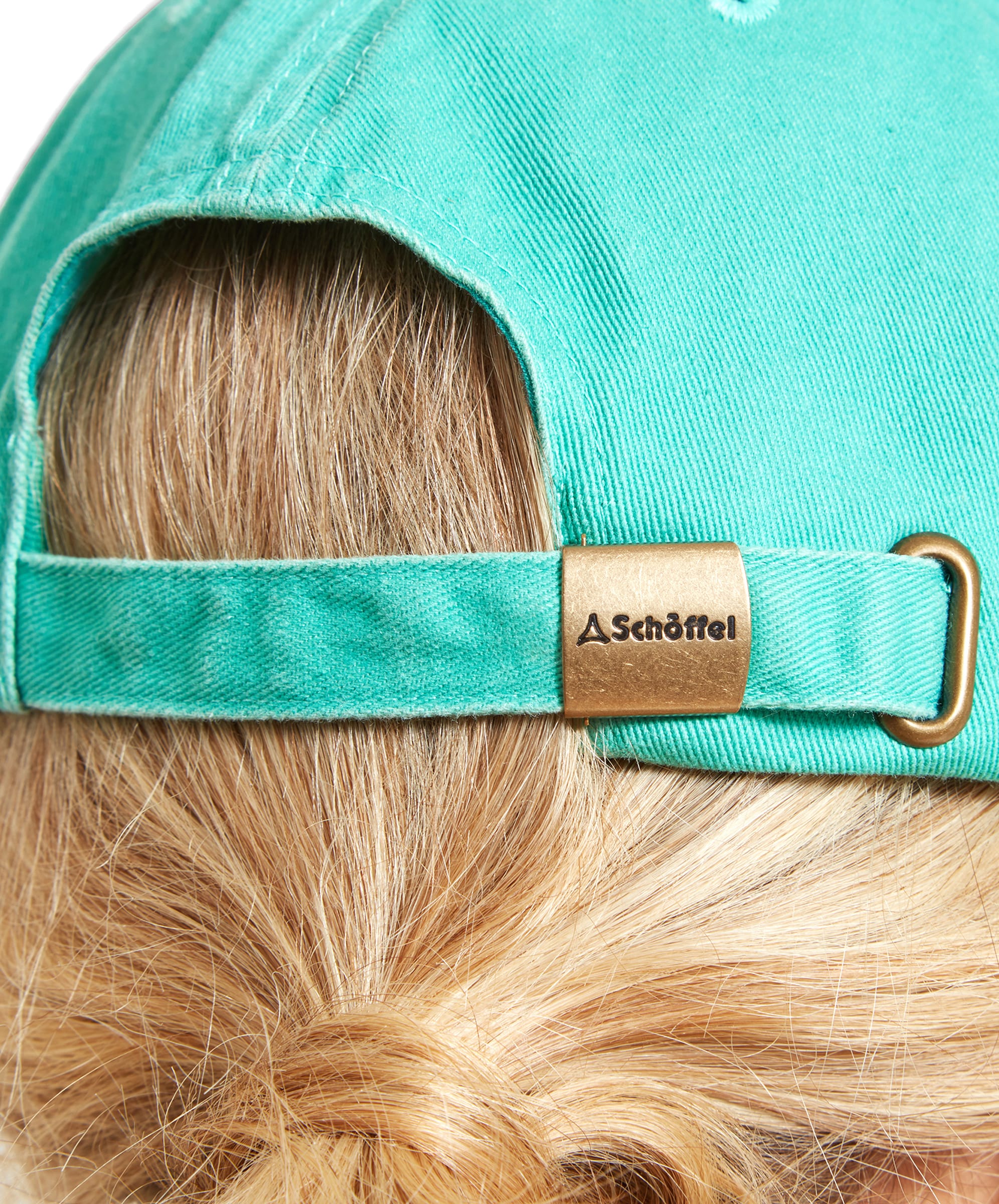 Close-up of the back of a Schöffel Unisex Thurlestone Cap in Bright Green, featuring an adjustable strap with a metal buckle engraved with the Schöffel logo. The cap is worn by a person with blonde hair tied in a low ponytail.