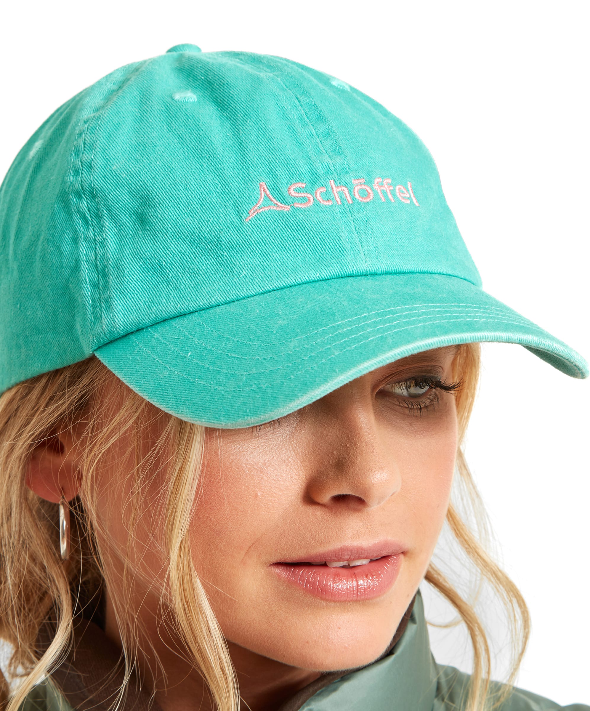 Front view of a woman wearing a Schöffel Unisex Thurlestone Cap in Bright Green with the Schöffel logo embroidered in pink on the front. She has light makeup, and her blonde hair is loosely pulled back. The cap is paired with a light green jacket.