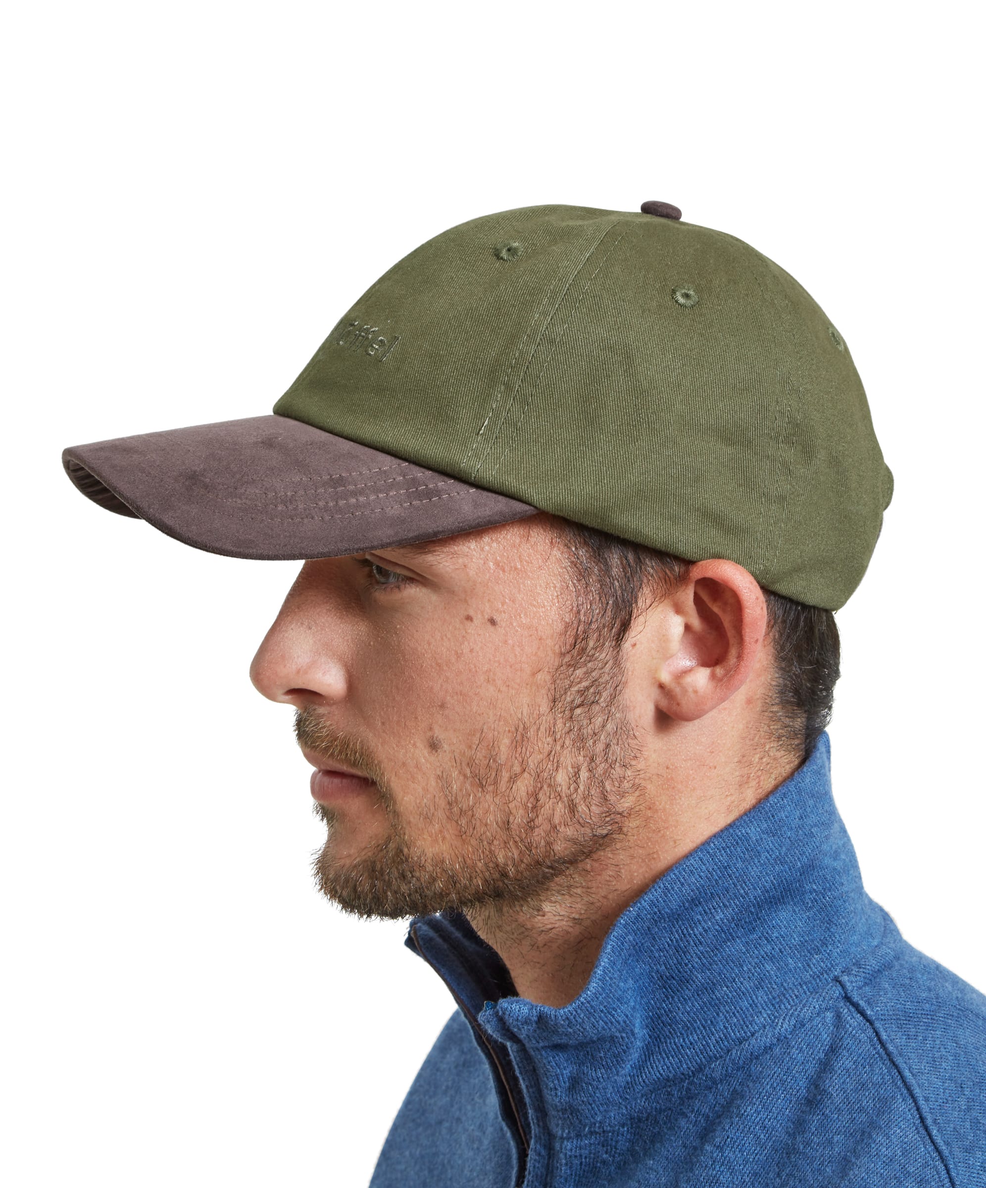 Side profile of a man wearing the Schöffel Unisex Thurlestone Cap in Green. The green fabric of the cap contrasts with the brown suede brim. The man’s facial hair and blue quarter-zip sweater complement the rugged, outdoor style of the cap.