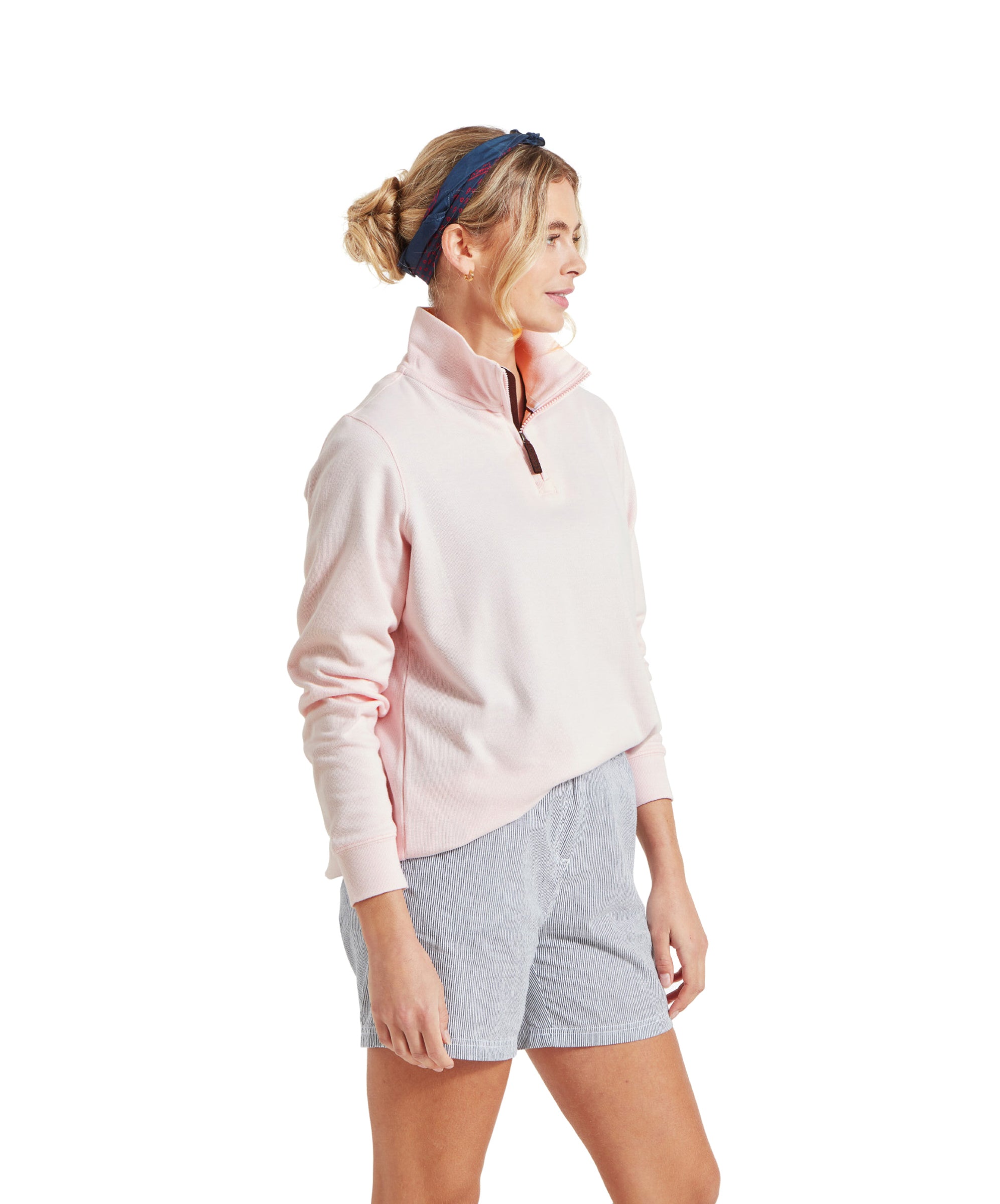 A model wearing a Schöffel Appletree Bay 1/4 Zip for Women in Pink with light blue striped shorts, a blue headband, smiling and looking to the side.