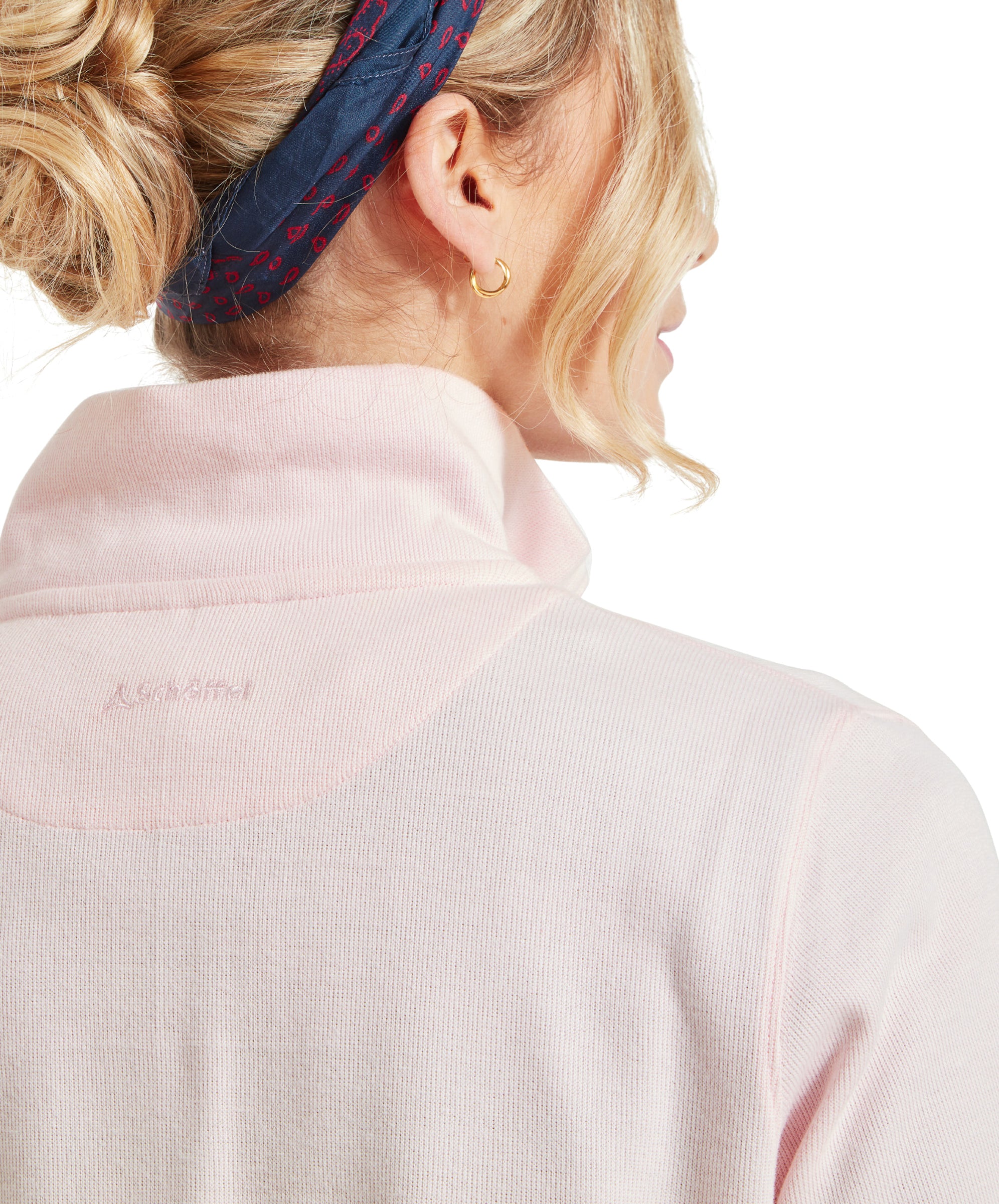 Close-up of a model's back, showing a Schöffel Appletree Bay 1/4 Zip for Women in Pink, blue headband, and gold earring.