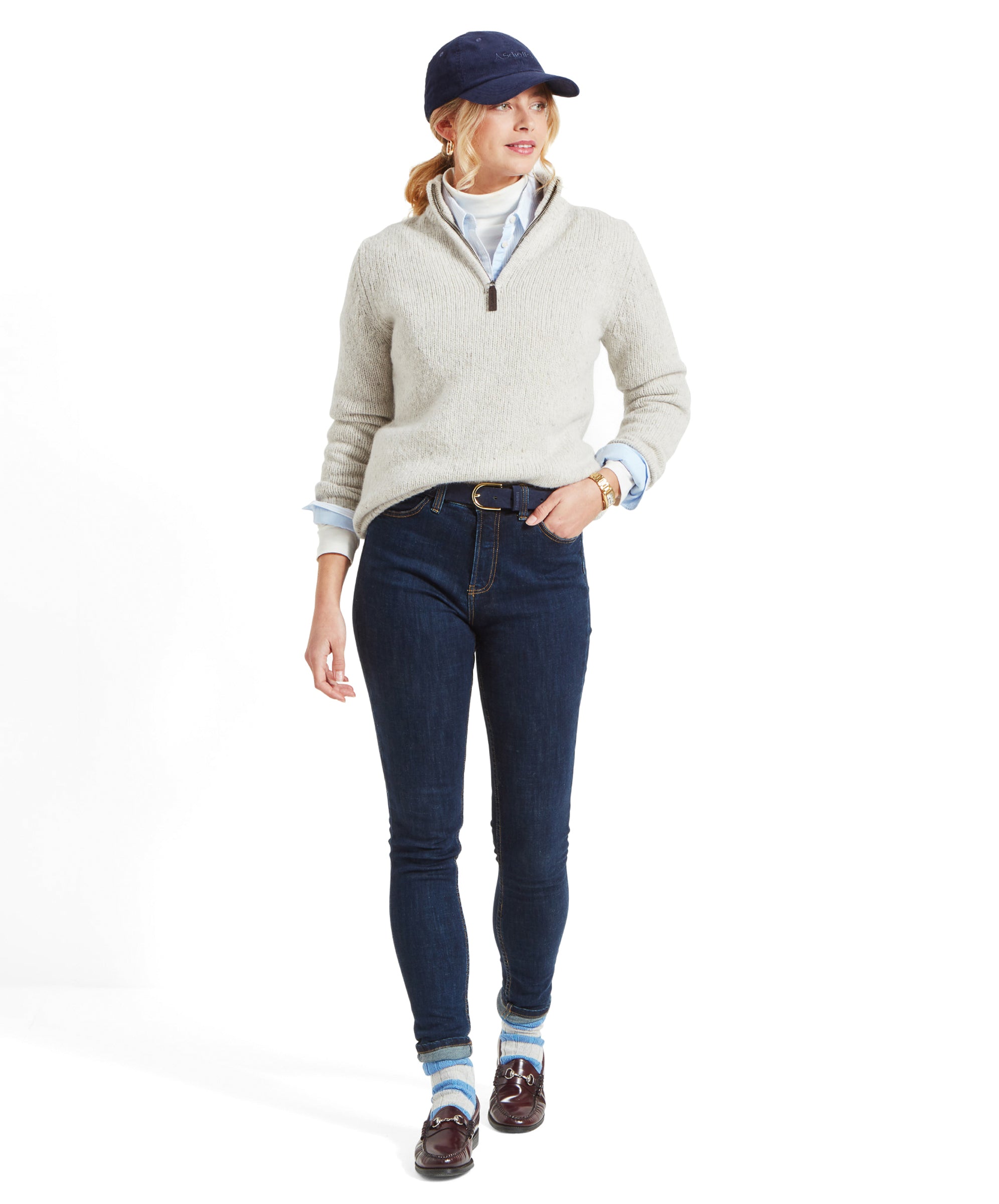 Full body shot of a woman in a Schöffel Women's Aviemore Alpaca Mix 1/4 Zip Jumper for Women in Cream, navy cap, and dark jeans, walking.