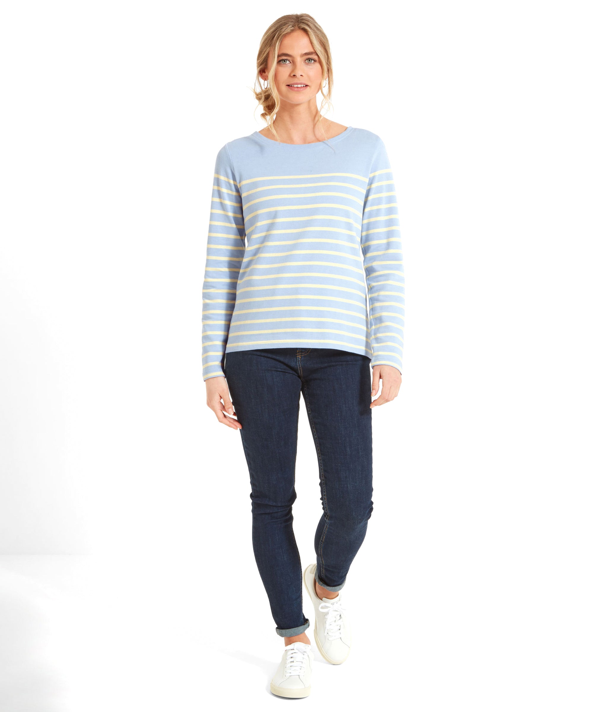 Full body view of a woman wearing a Schöffel Beauport Top for Women in Yellow, dark blue jeans, and white trainers.