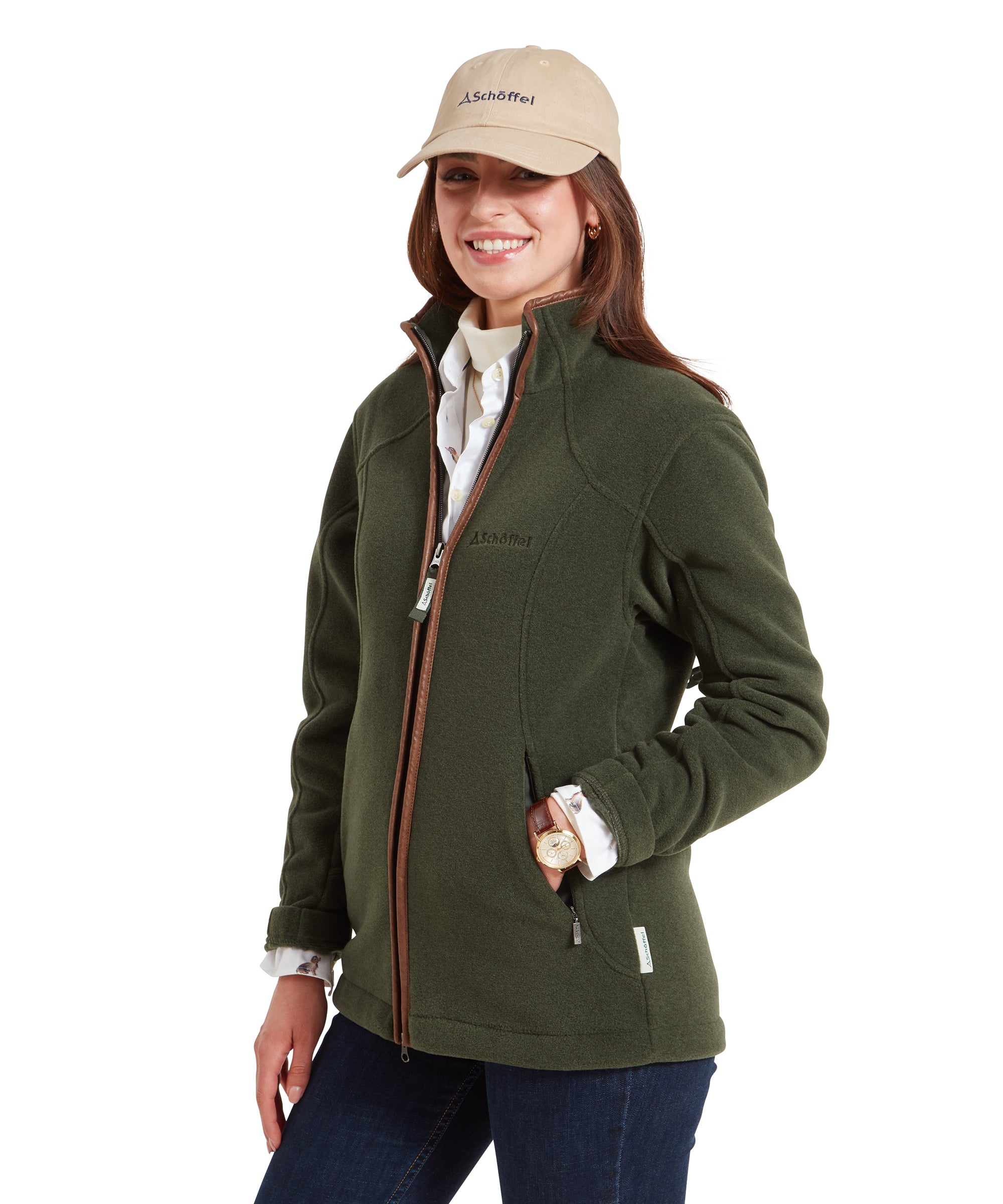 A side view of the woman wearing the Schöffel Burley Fleece Jacket for Women in Green, showing the details of the jacket's fit and the beige cap. She is smiling and holding the jacket's collar with one hand.