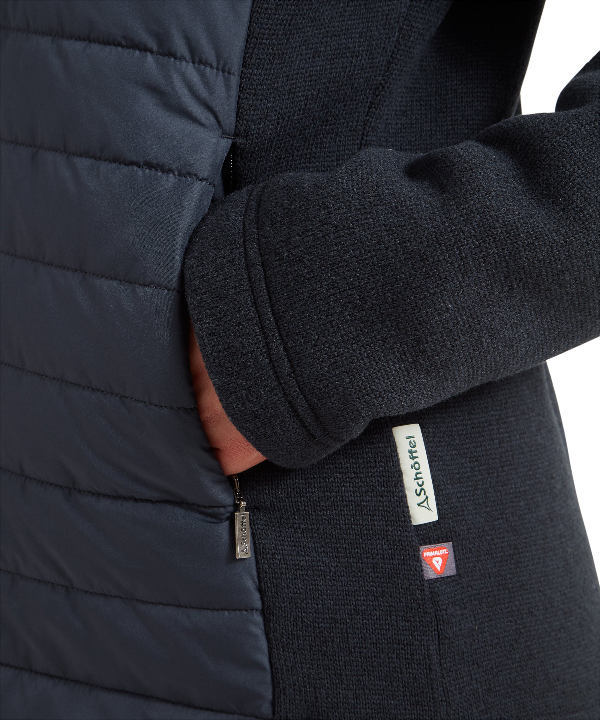 Close-up of the pocket area on a Schöffel Burley Hybrid Jacket for Women in Blue, with a hand partially inside the pocket and a Schöffel logo tag visible.